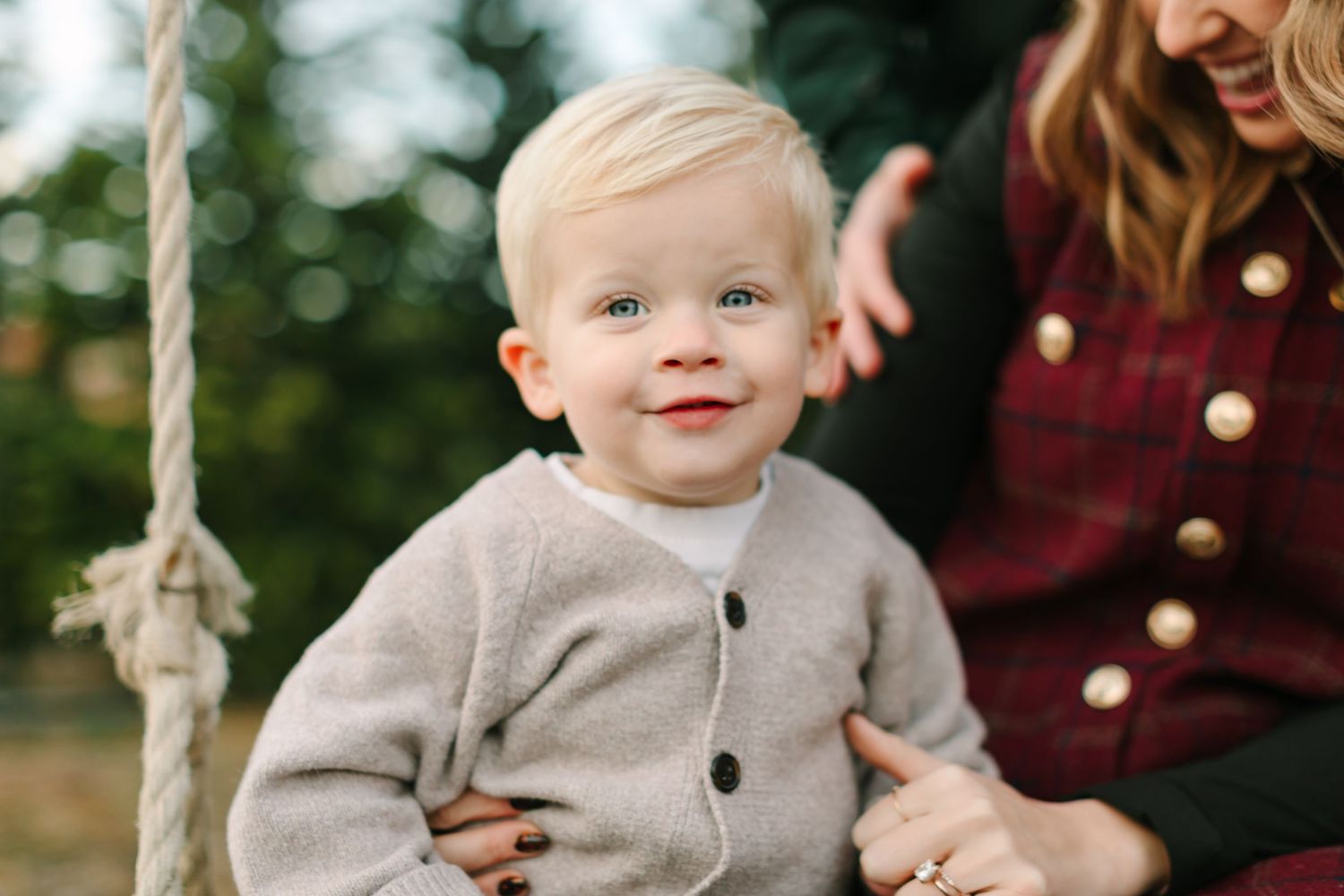 Young boy portrait at a pine tree farm in Riverton, Utah in Utah County at the Kinlands while his mom sits next to him.