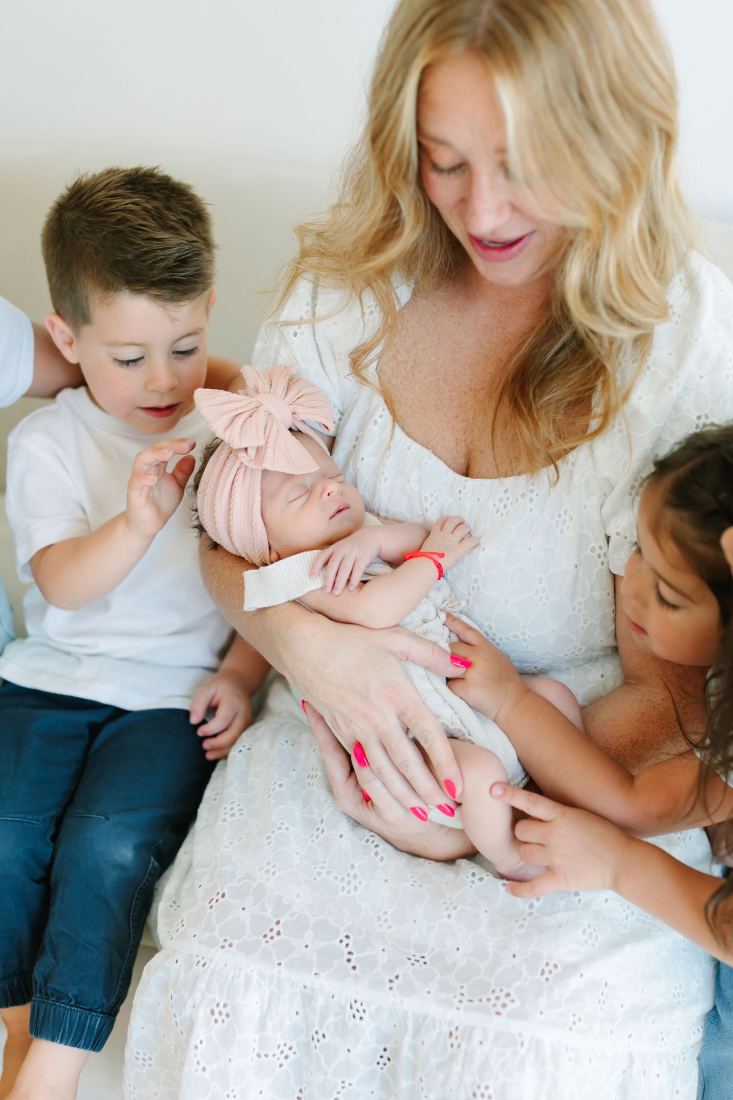 A newborn baby being cradled and admired by family members in a bright white setting.