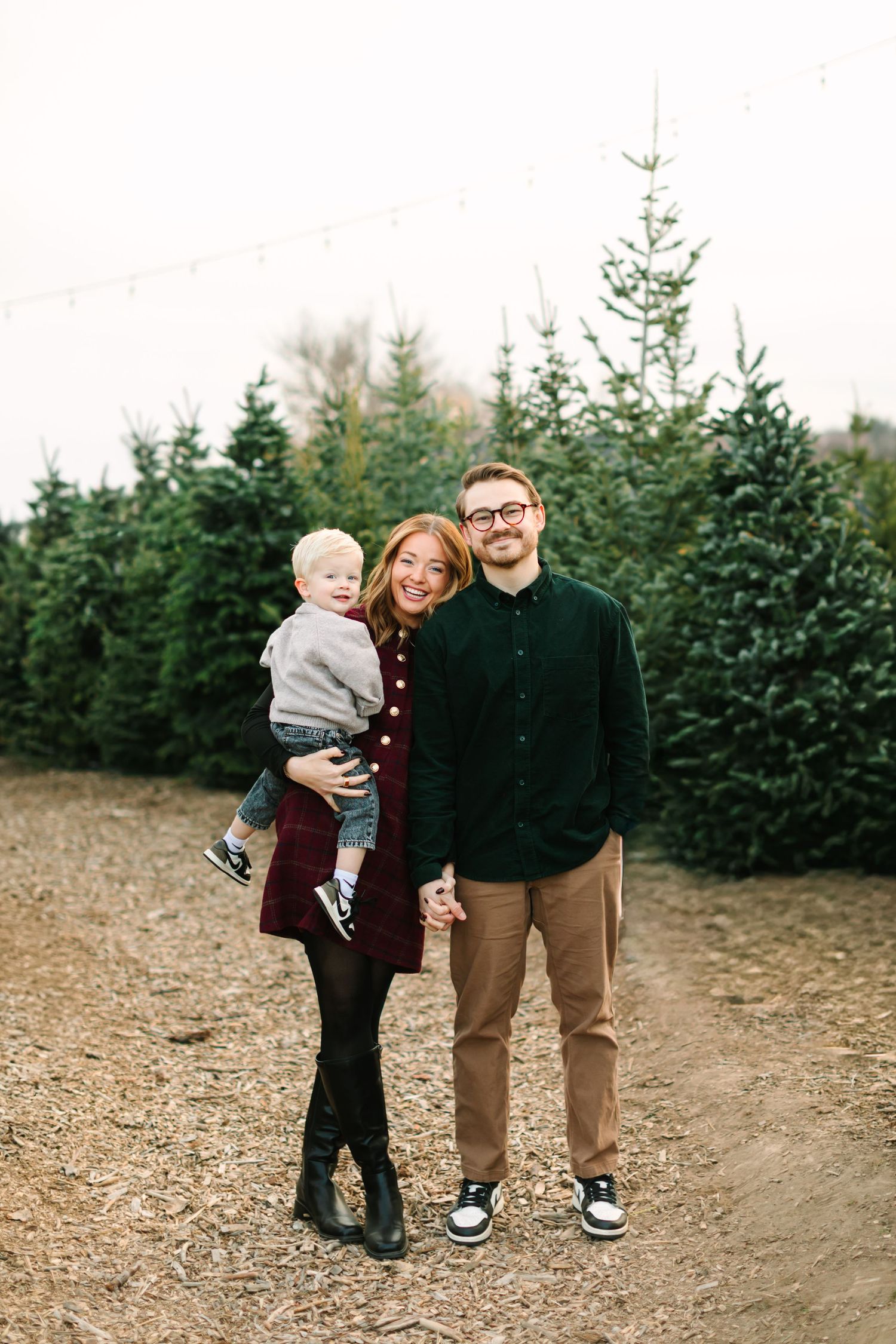A group stands together at a Christmas tree farm on a cloudy winter day.