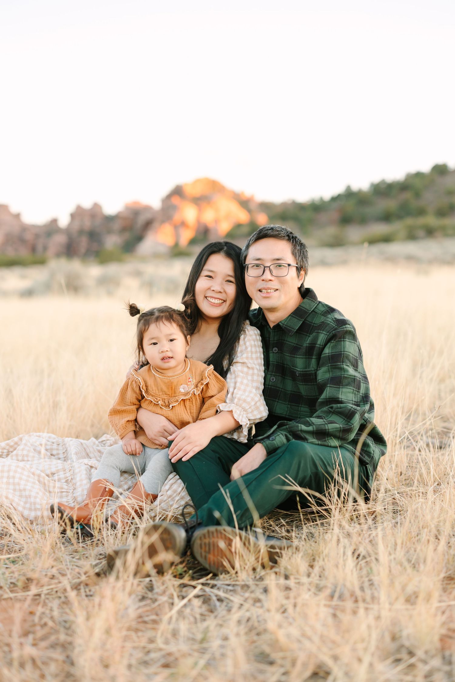 Family sitting together in golden grass field during sunset at Garden of the Gods park.