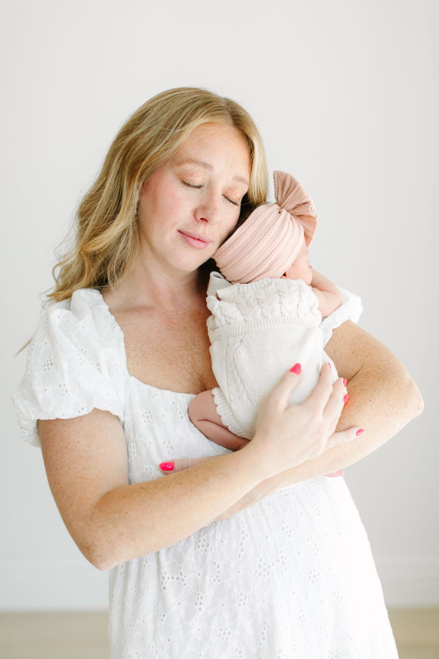 A series of tender moments captured between a mother in white lace and her newborn baby against a light background.