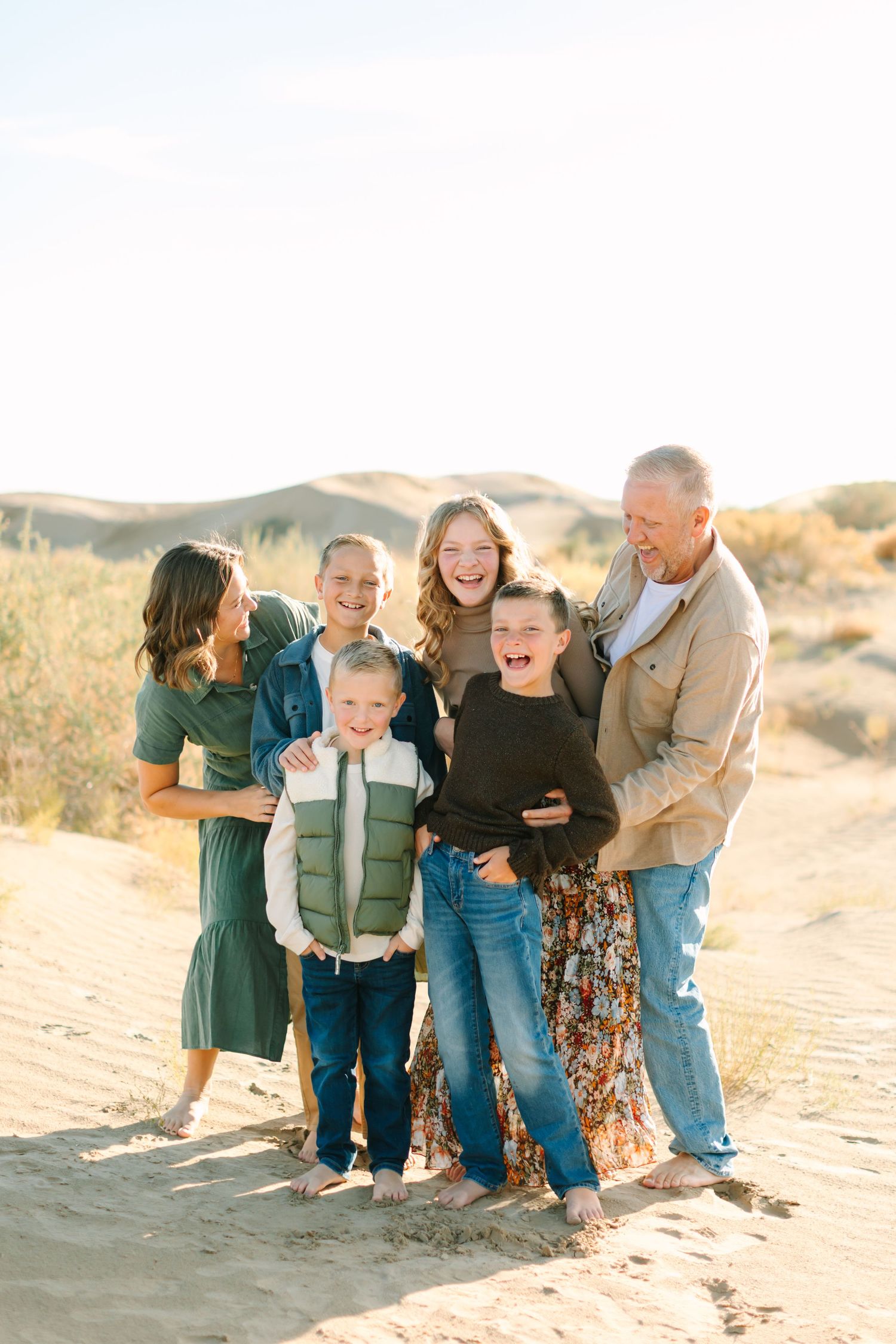 A group enjoying a candid moment together on sandy dunes during a warm sunset photoshoot.