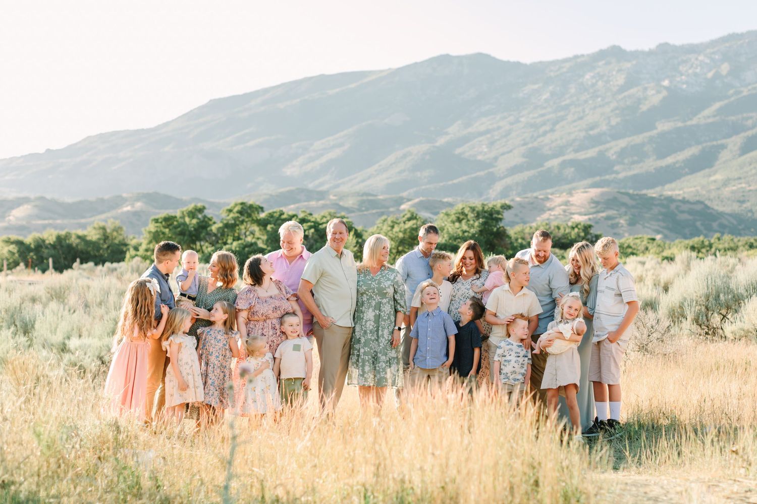 A group stands together in a golden field at sunset with mountains in the background creating a panoramic view.