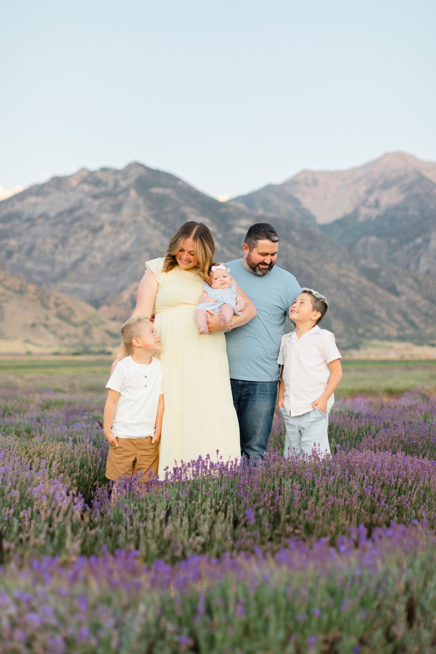 A family shares joyful moments together in a beautiful purple lavender field with mountains in the background.
