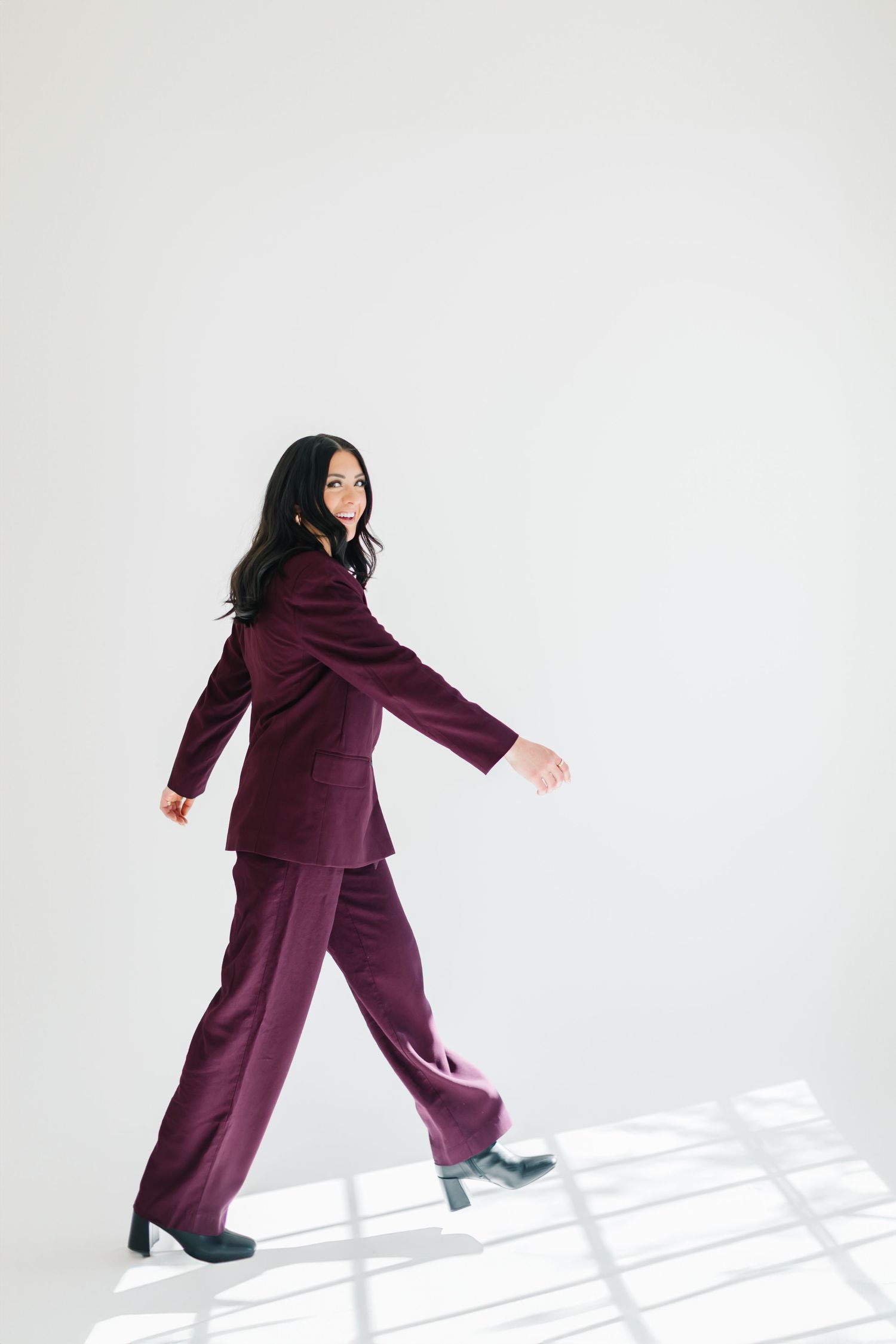Playful movement shots in a purple suit with dramatic shadows on white background at White Space Studios in Provo, Utah in Utah County..