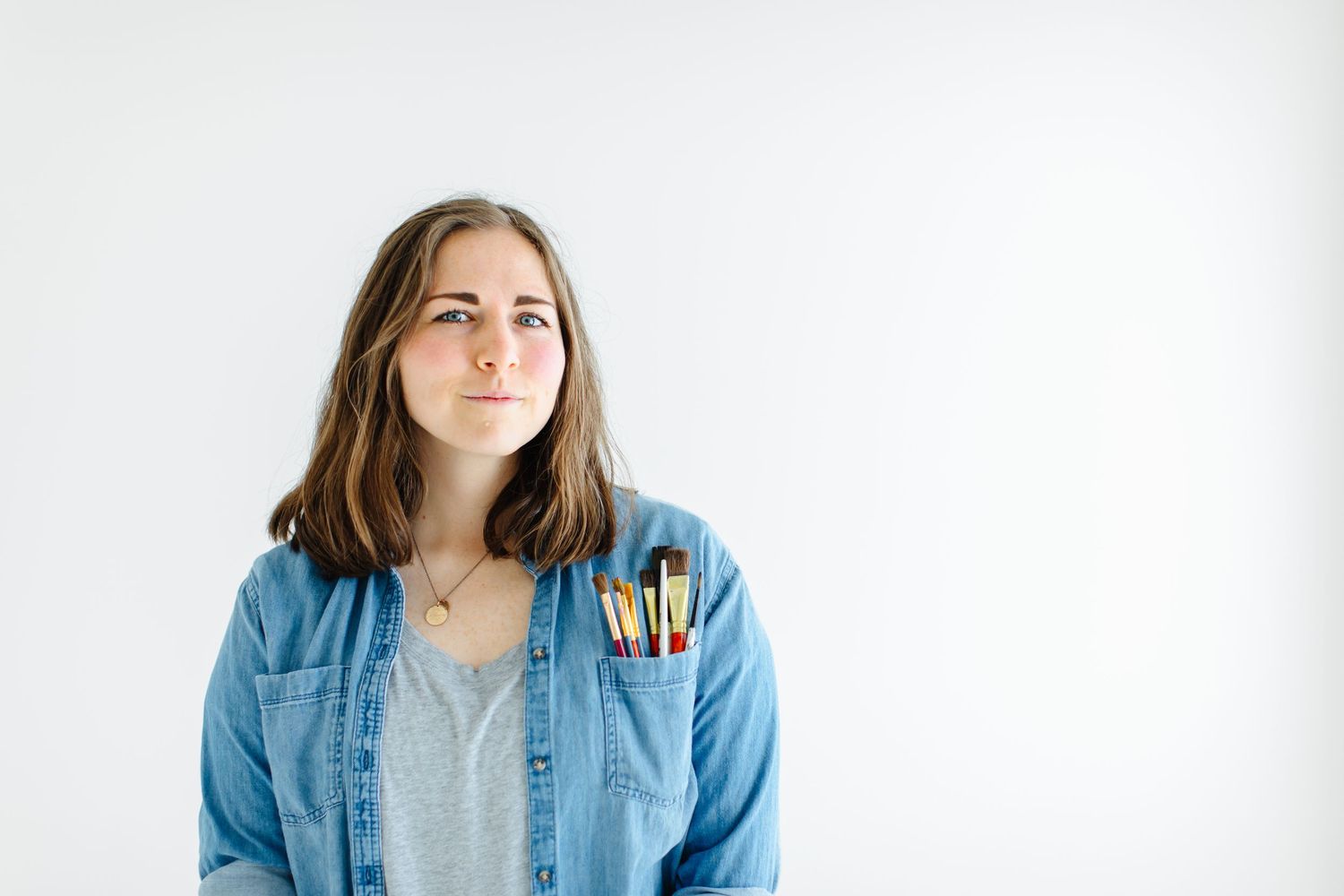 Creative wearing denim shirt and colorful pants stands against white background at White Space Studios in Provo, Utah in Utah County..