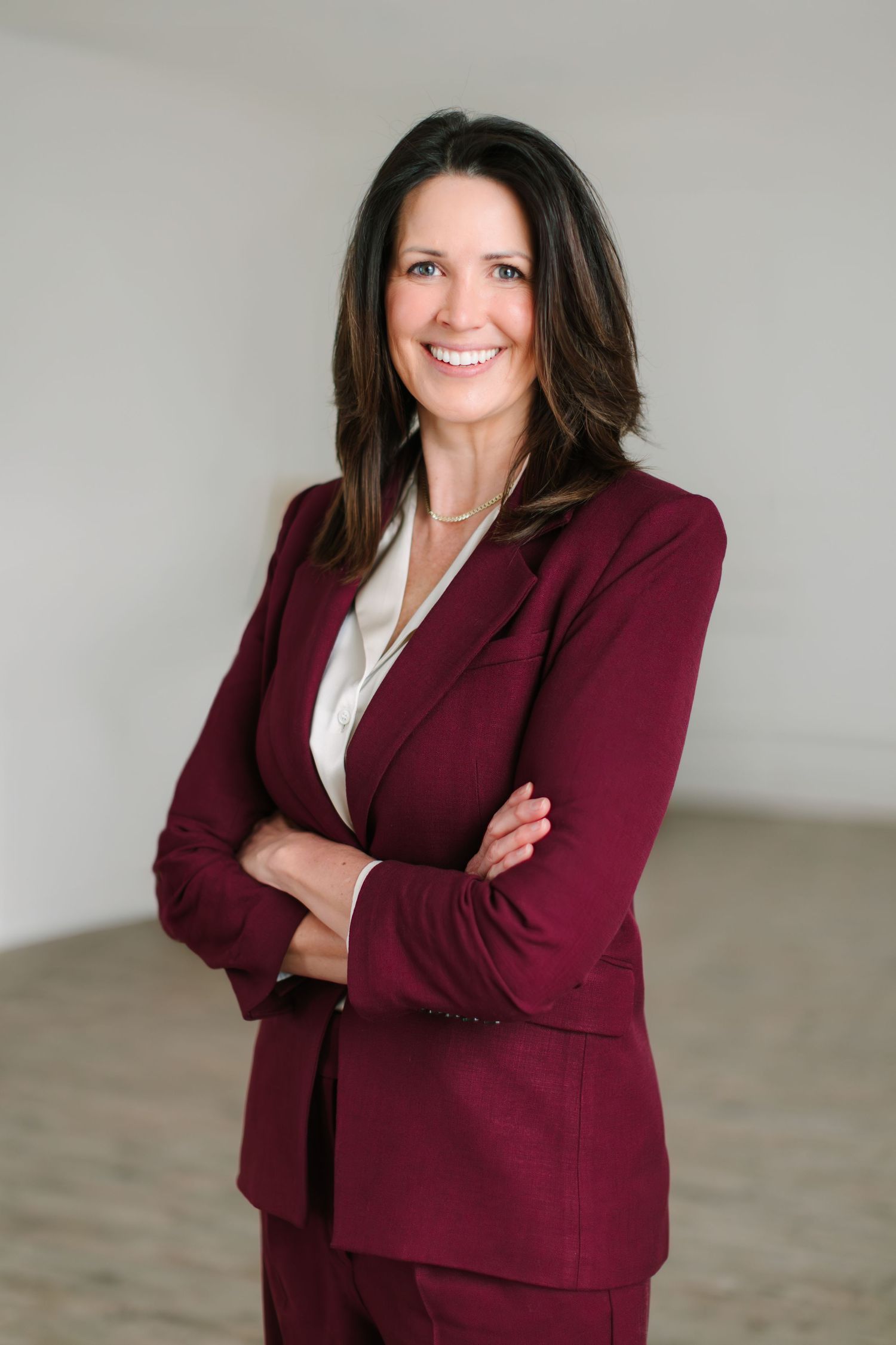 Professional business portrait series showing a burgundy blazer against a neutral gray studio background.
