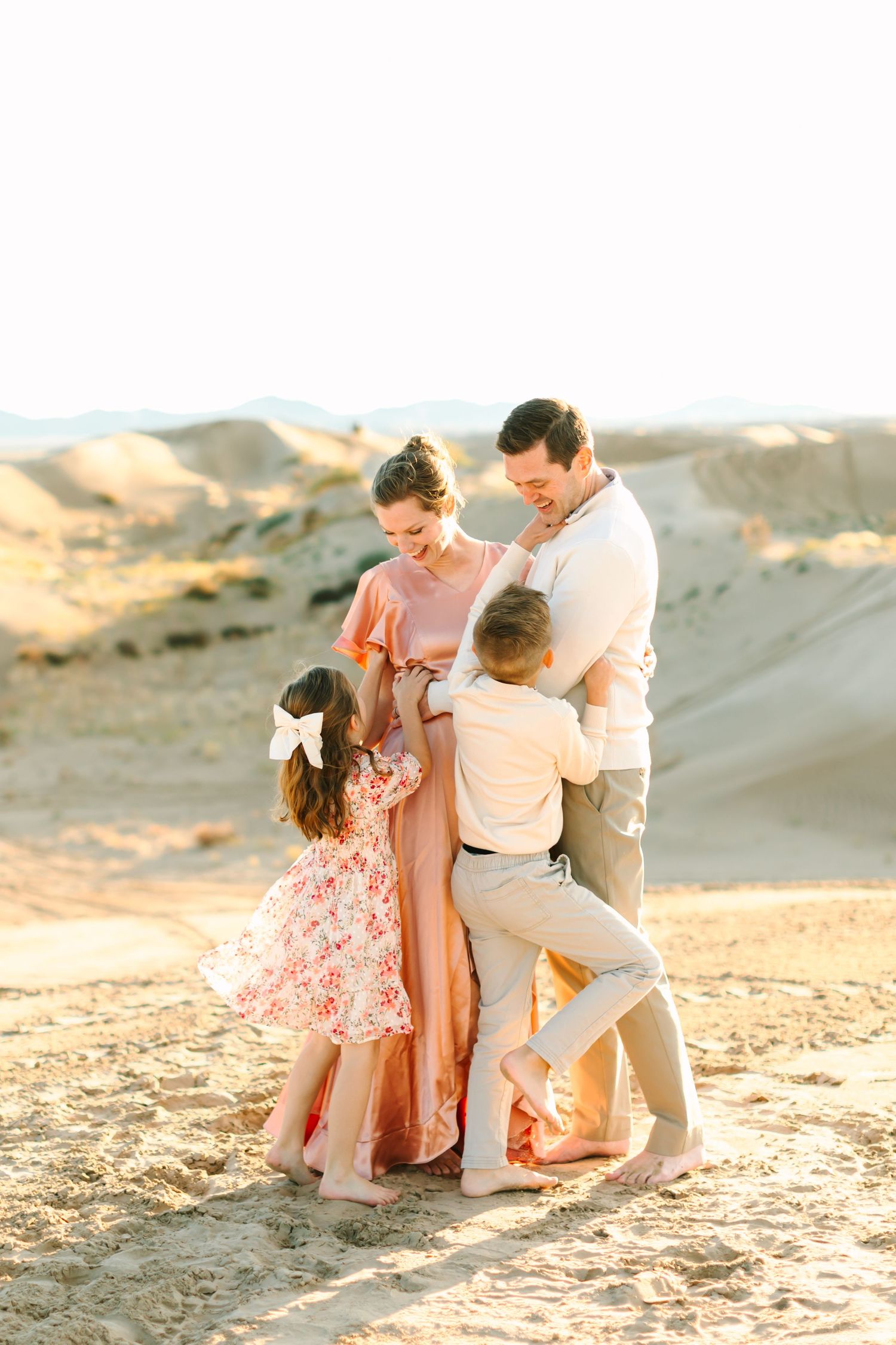 A family plays together on a sandy beach during golden hour sunset creating joyful candid moments.