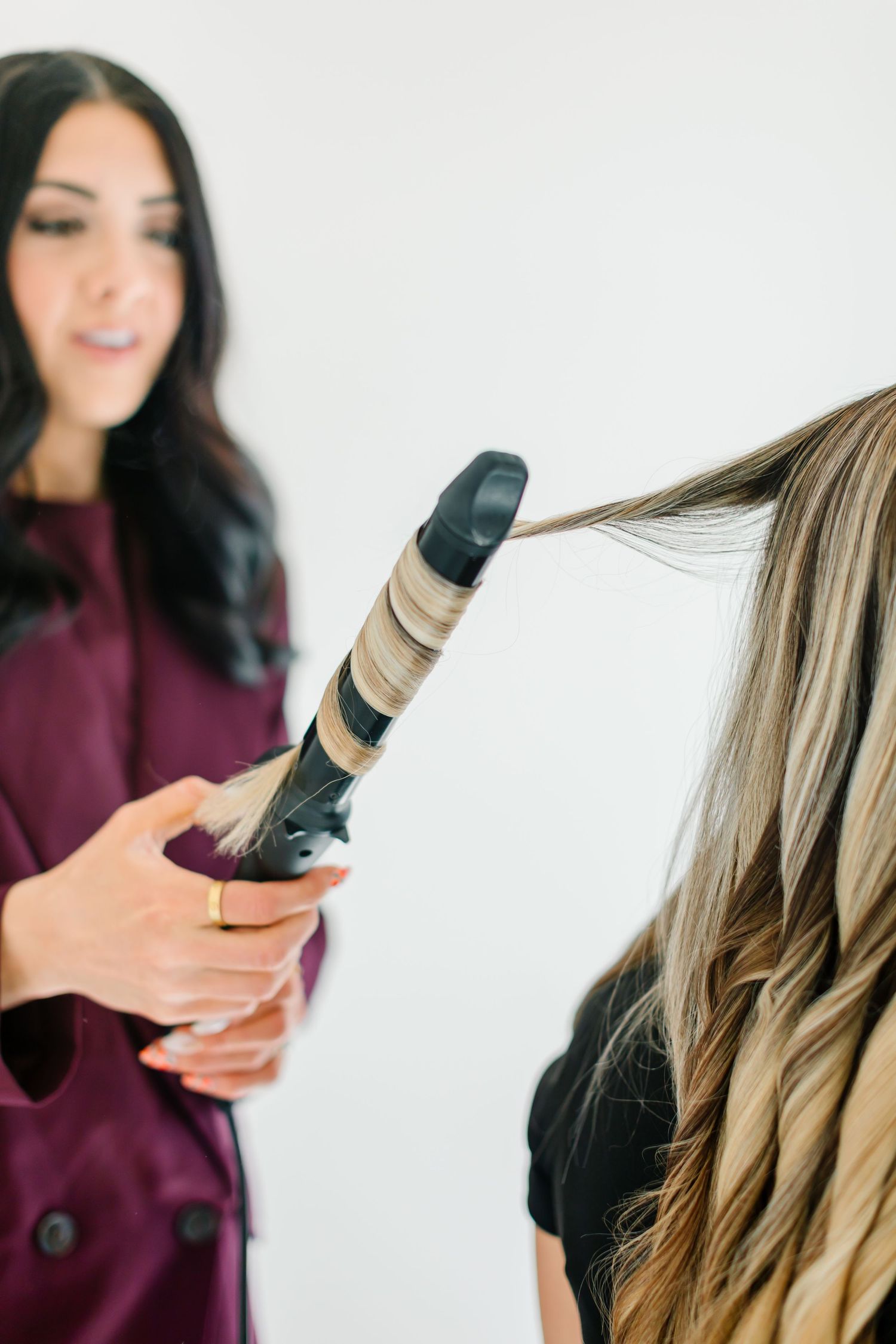 Professional using curling iron to style long blonde hair in bright studio setting at White Space Studios in Provo, Utah in Utah County..
