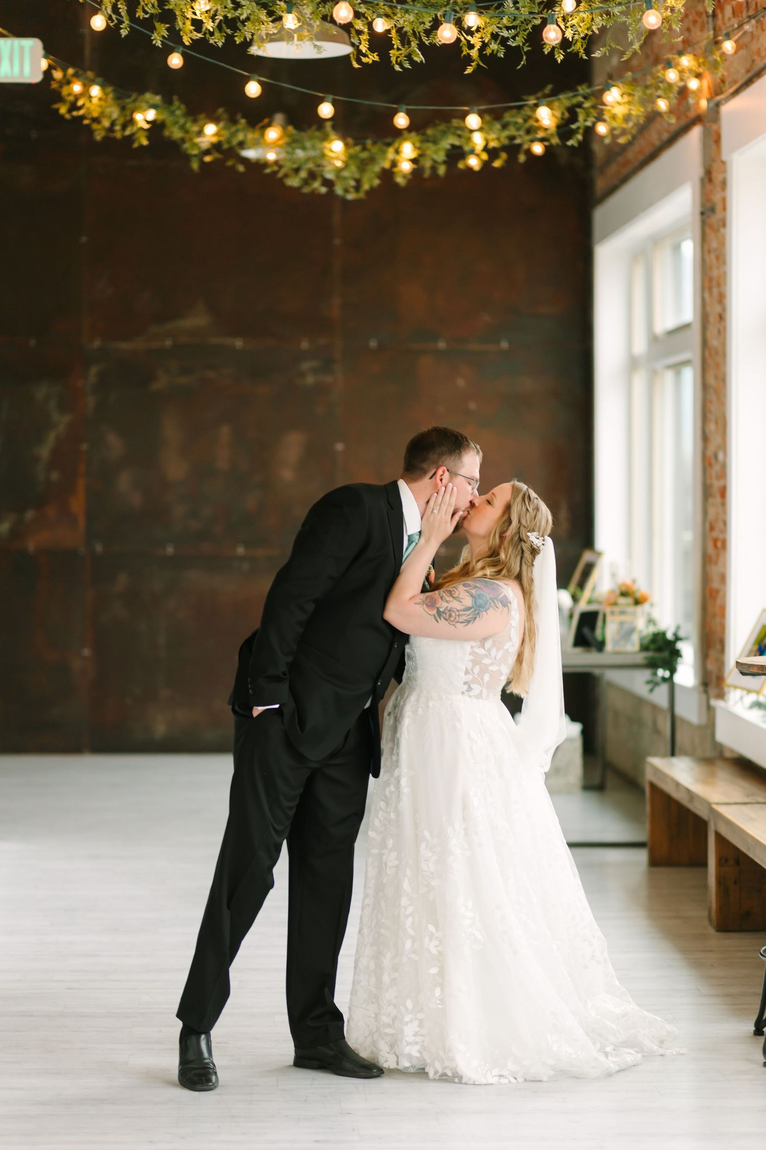 A romantic wedding sequence showing a couple sharing a dip kiss under twinkling string lights and greenery decor.