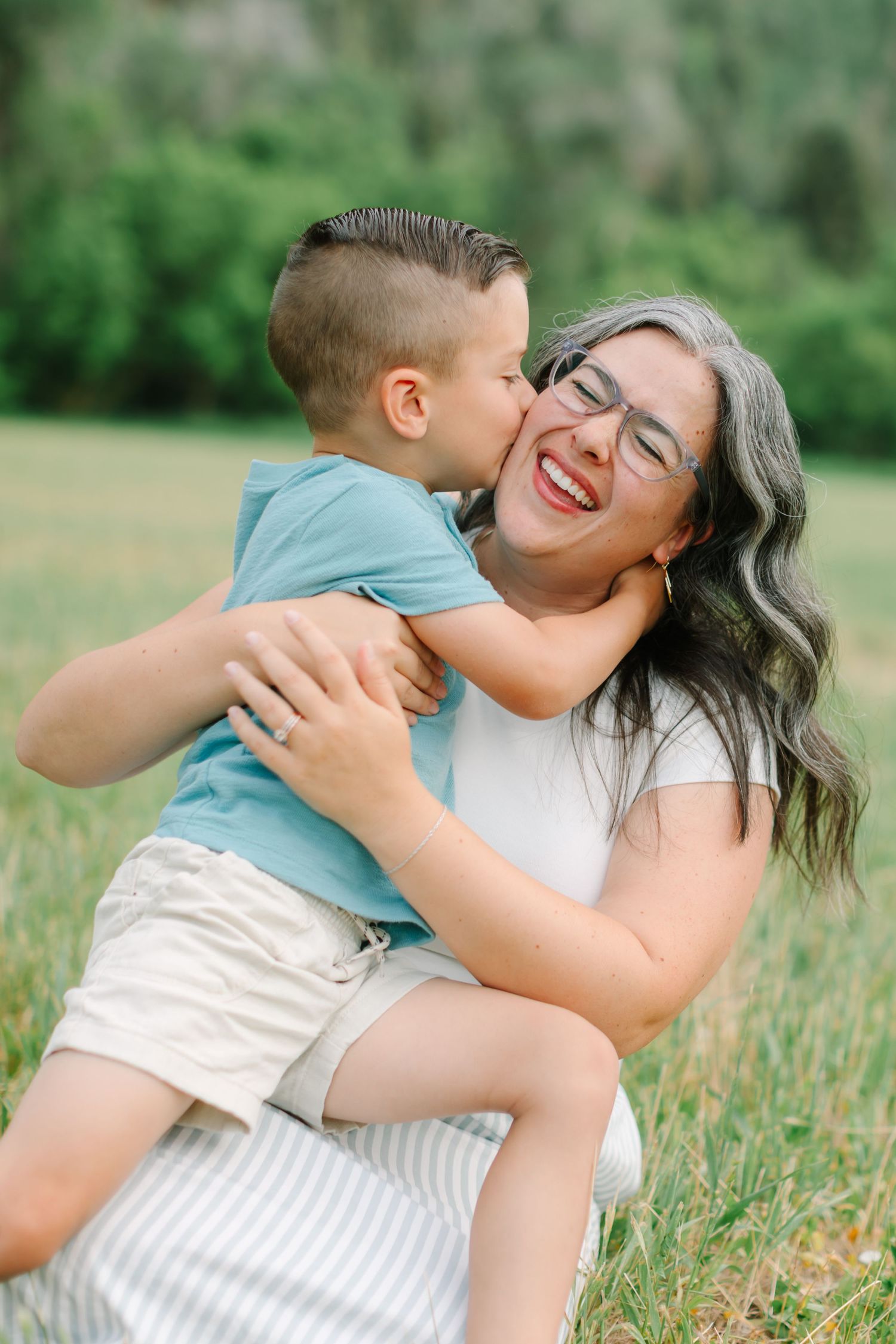 A tender moment captured in a grassy field on a sunny day with warm natural lighting.