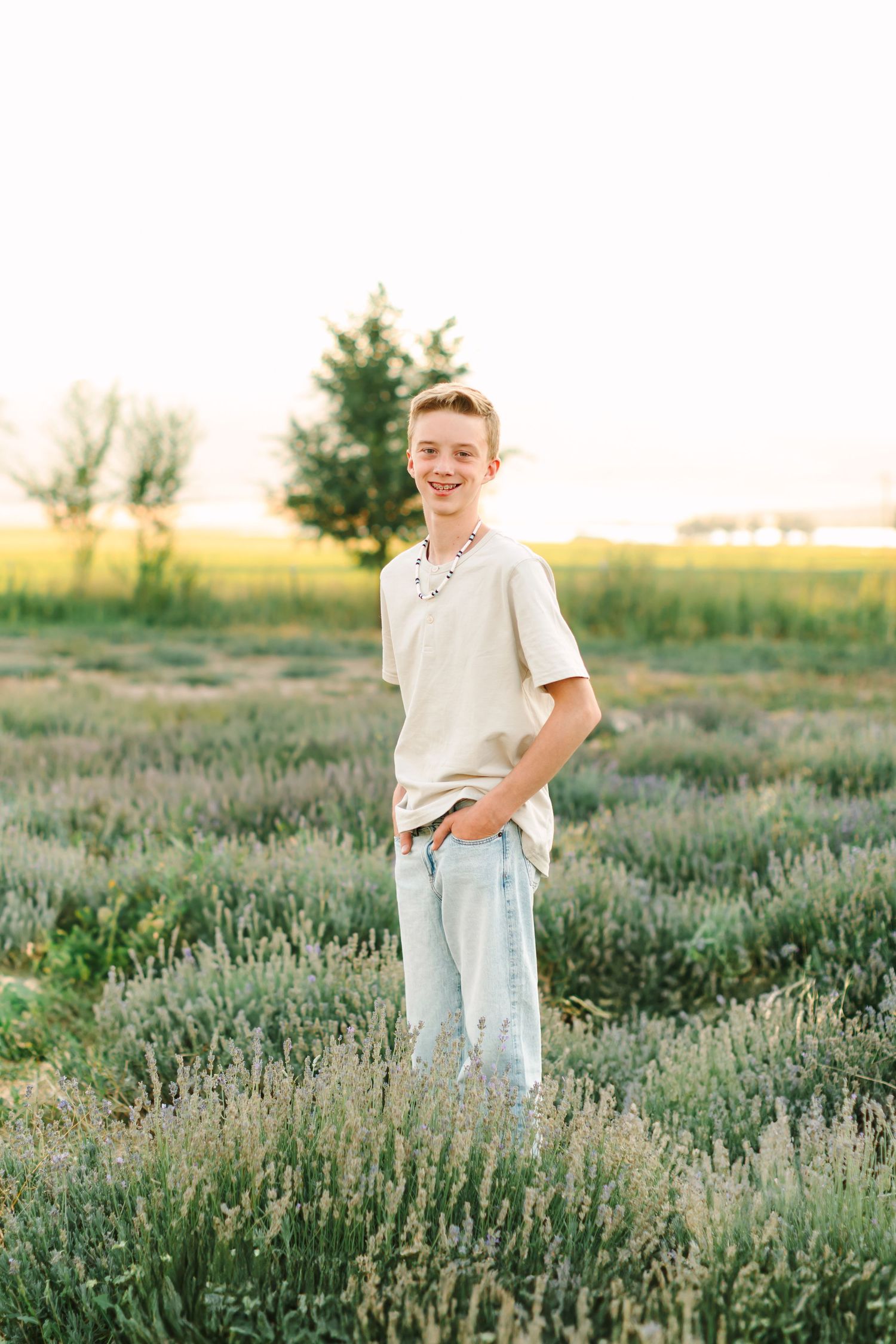 A person stands joyfully in a blooming lavender field at sunset with golden light filtering through the plants.