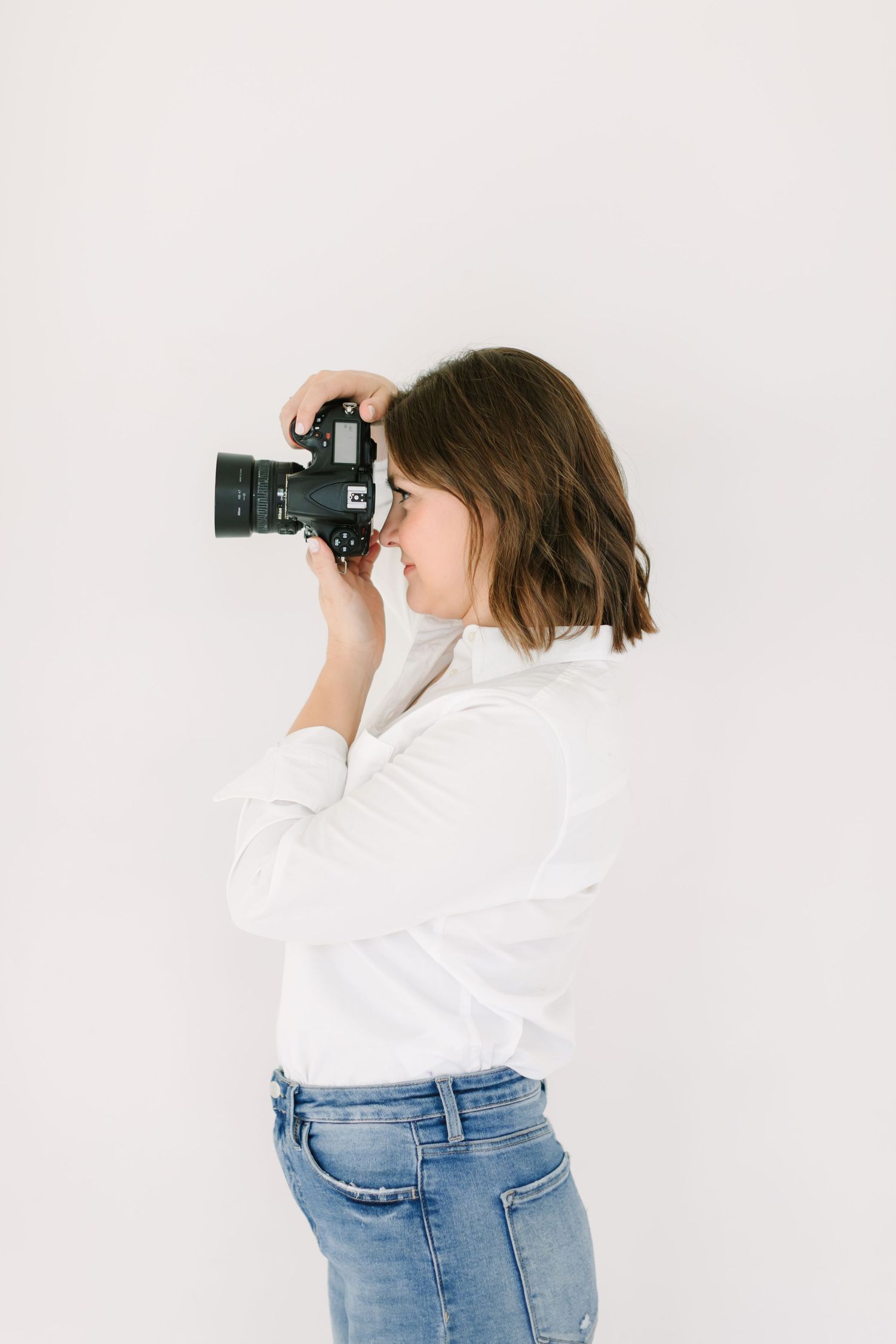 Person in white shirt and jeans photographing with a camera shown in three different angles against white background.