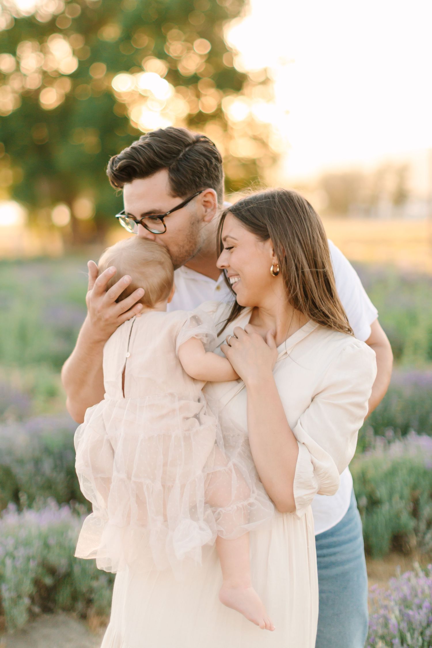A couple embraces tenderly in a lavender field at sunset with soft golden lighting.