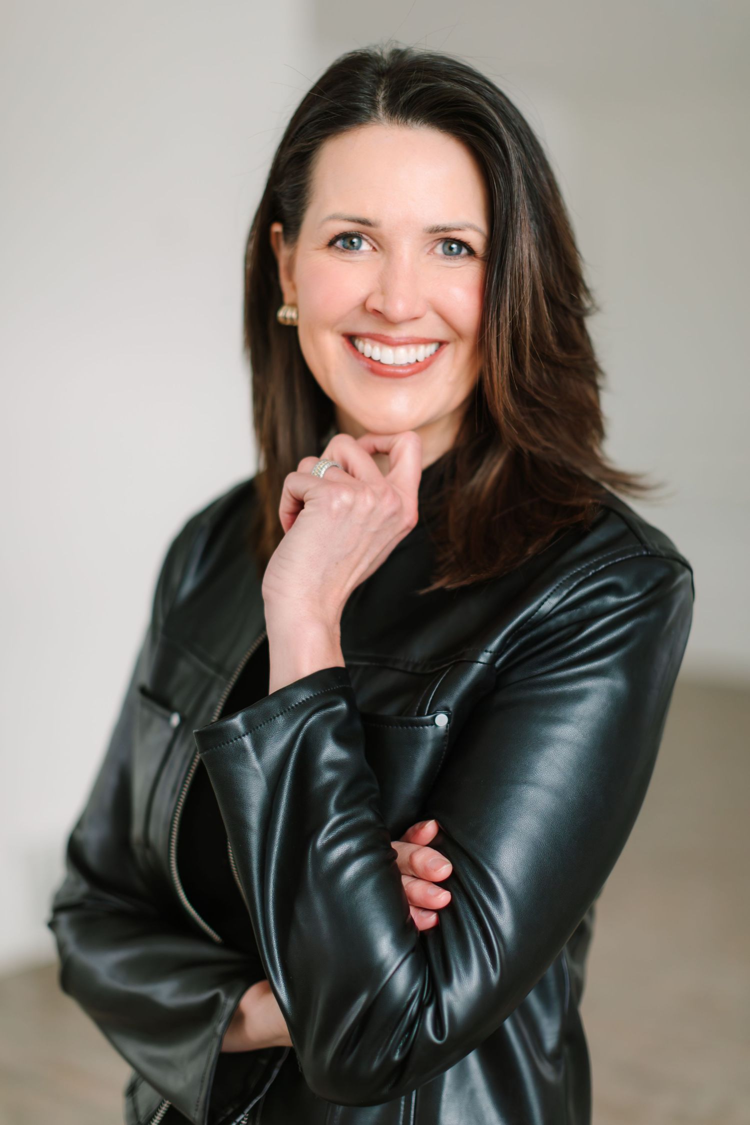 Professional portrait series showing someone in a black leather jacket posing against a light background with warm expressions.