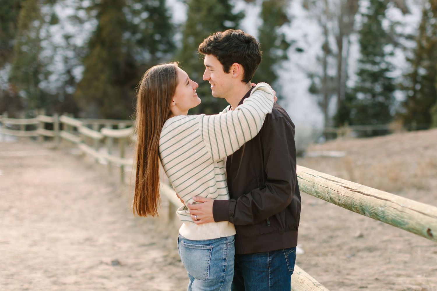 A couple embraces tenderly on a scenic hillside path during a romantic outdoor photoshoot.