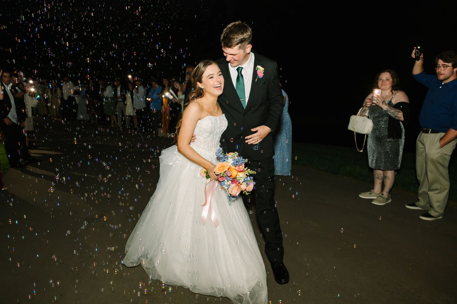A couple dances at their wedding celebration while guests throw confetti in a joyful nighttime celebration.