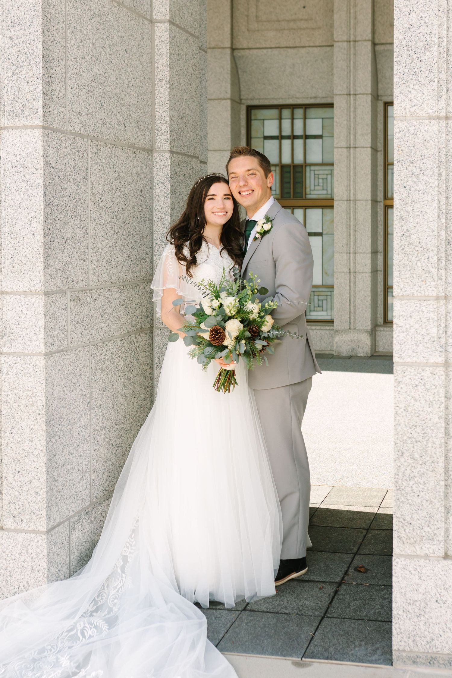 A couple stands under a beautiful arch on their wedding day in Springville, Utah.