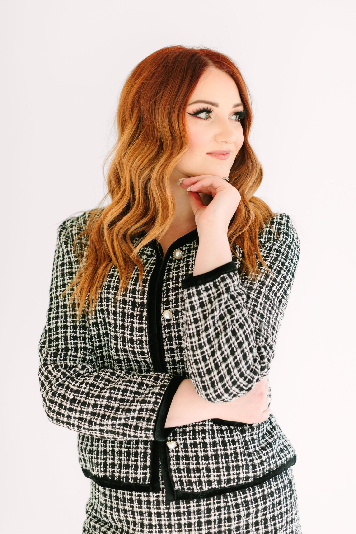 Fashion model in black and white tweed jacket poses thoughtfully against white background in four similar poses.