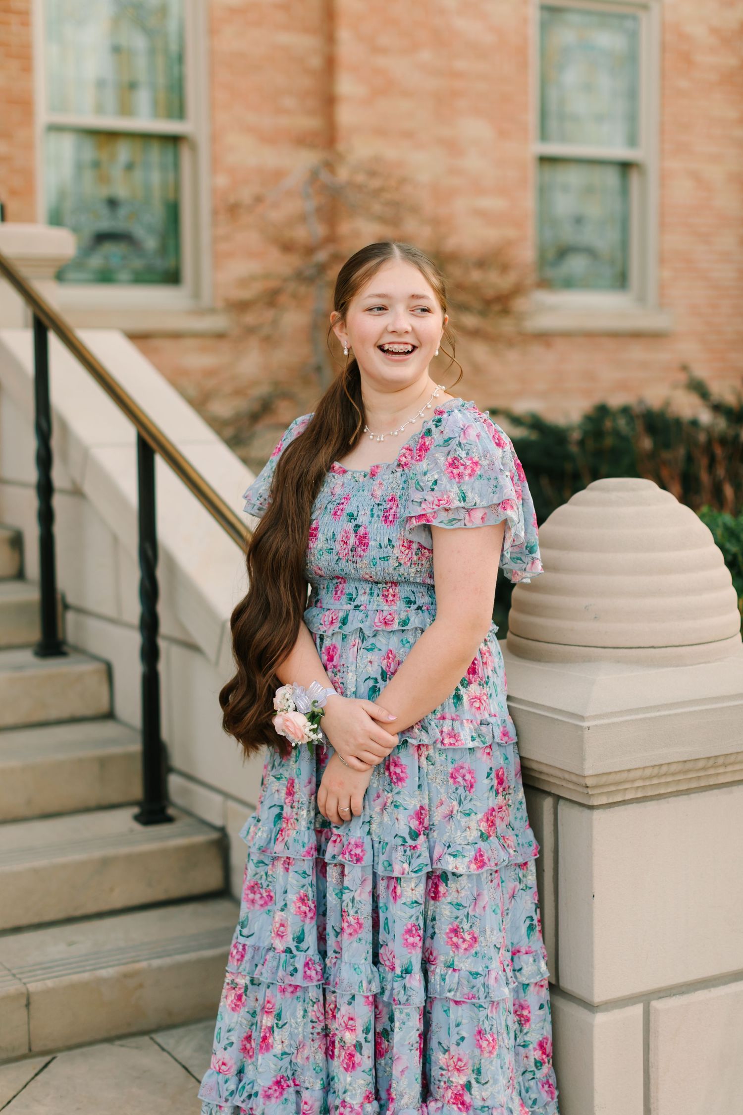 A floral dress with blue and pink patterns is shown in a series of photos against a brick building backdrop.