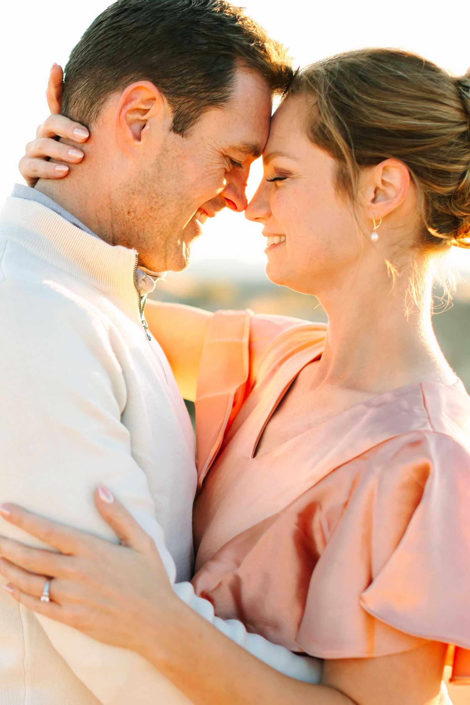 A romantic couple shares an intimate moment at sunset with warm golden light illuminating their tender embrace.
