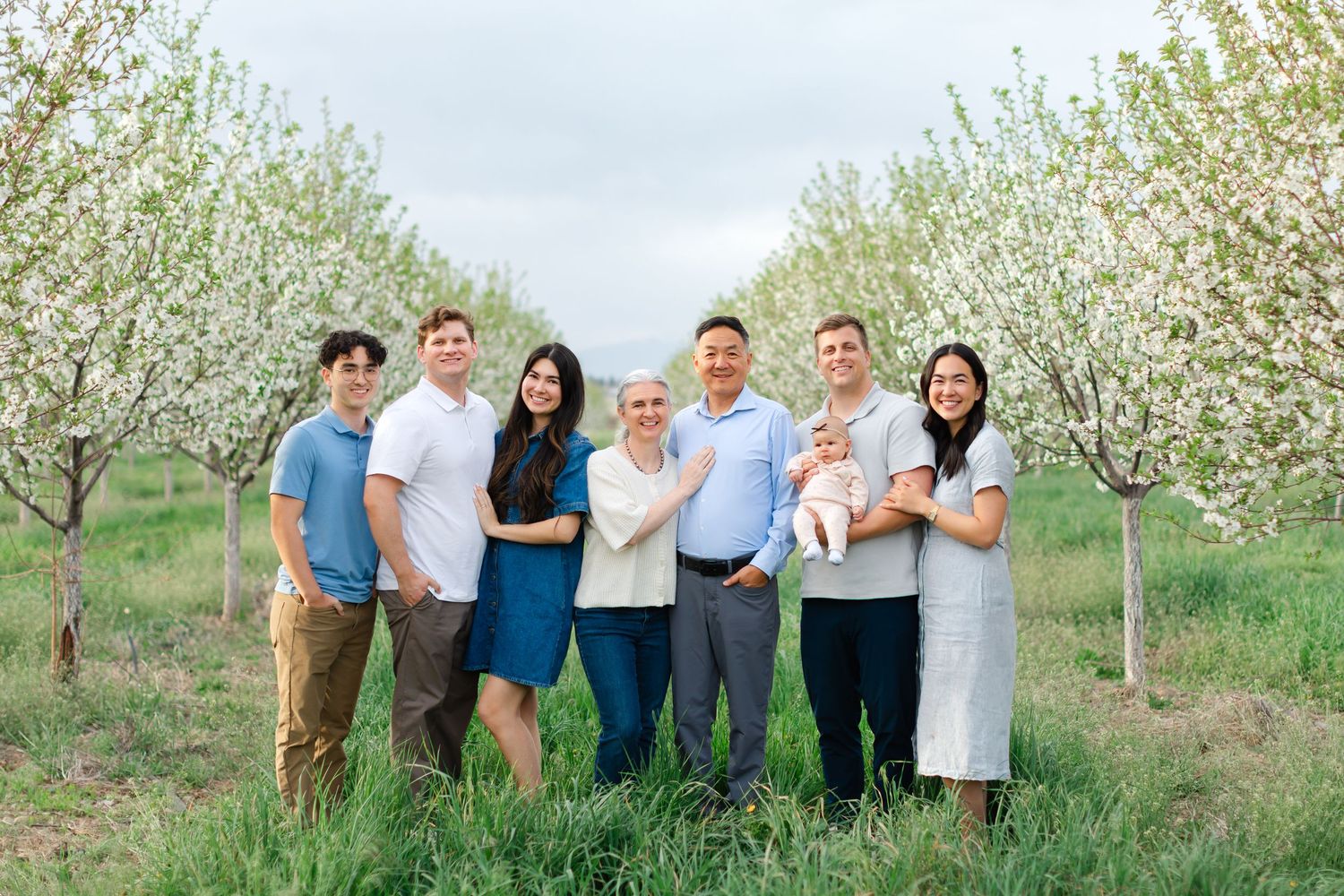 A group stands together in a blooming apple orchard during springtime for outdoor portraits.