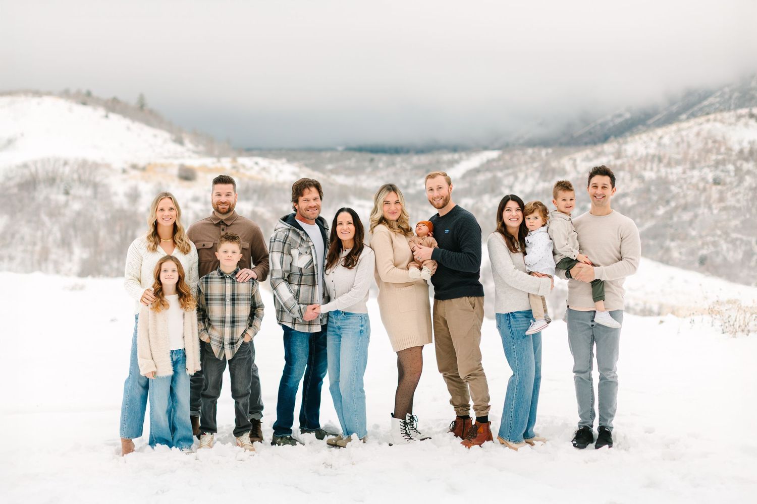 An extended family is standing in a beautiful winter scene with lots of snow for their family photoshoot in Salem, Utah.