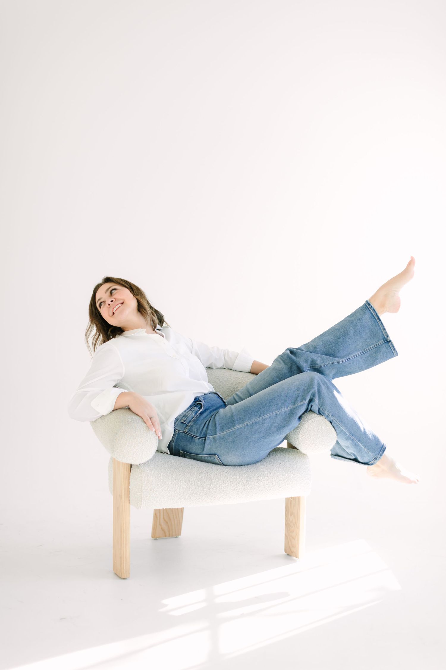 A person in blue jeans and white shirt lying sideways across white blocks in four artistic poses against a white background.