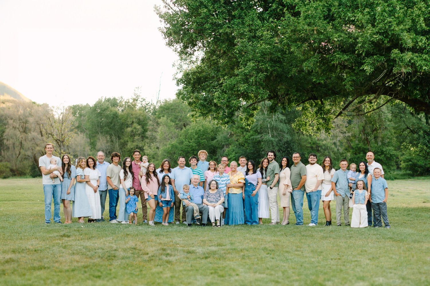 An extended family session surrounded by green trees and grass at Jolley's Ranch in Spanish Fork, Utah.