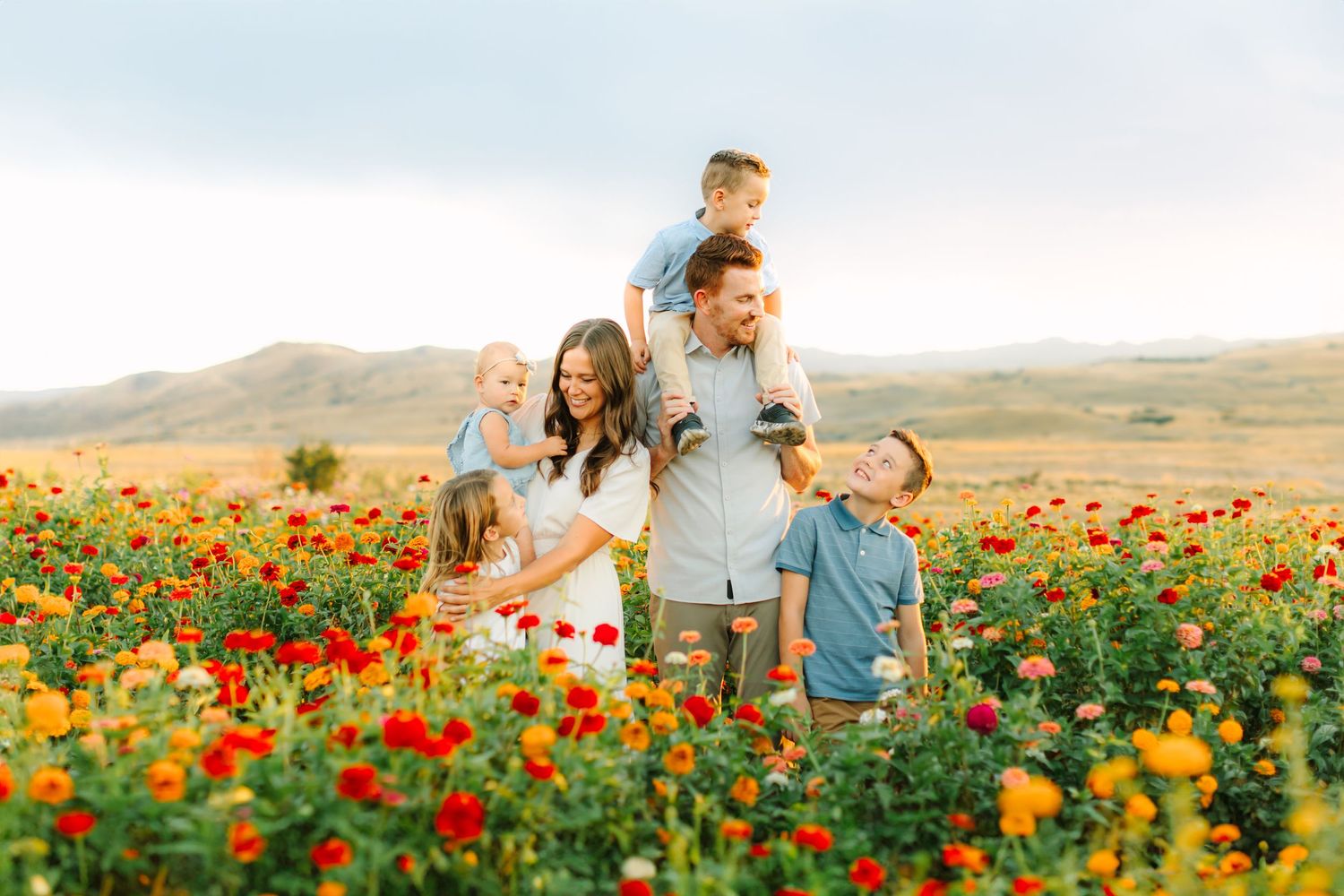 People enjoying a romantic moment together in a vibrant field of red and yellow wildflowers at sunset.