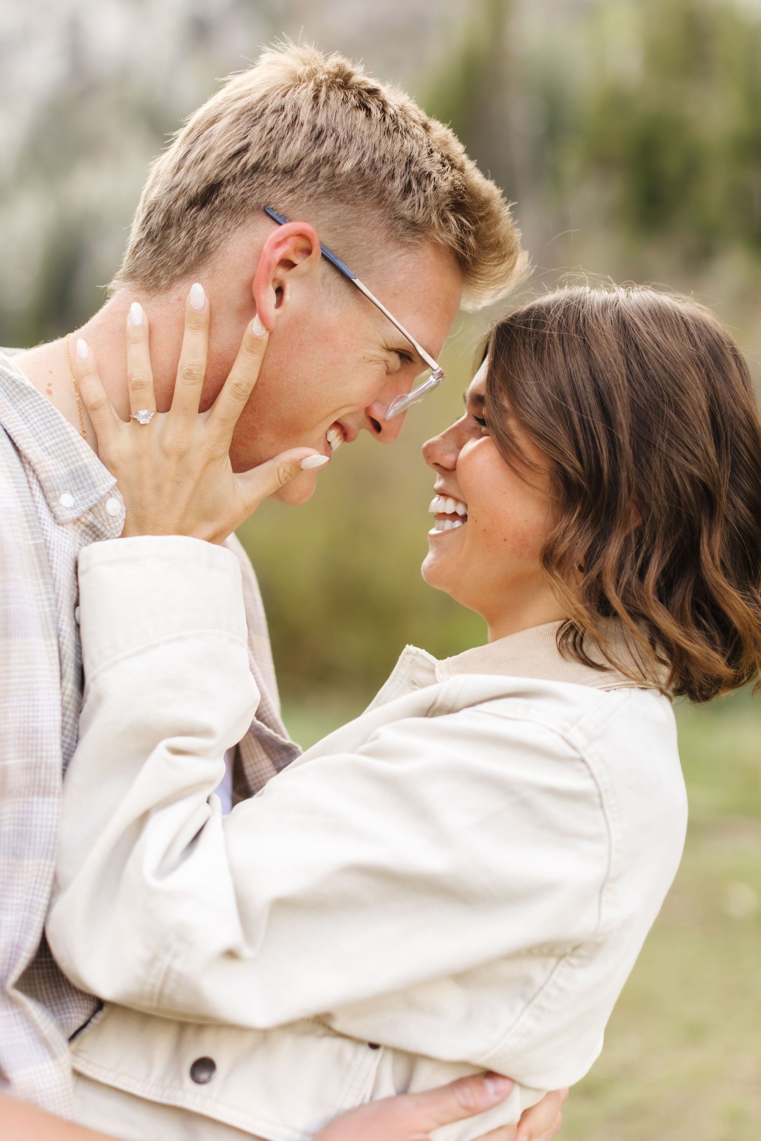 Happy couple sharing a romantic moment outdoors, woman showing engagement ring while smiling face to face.