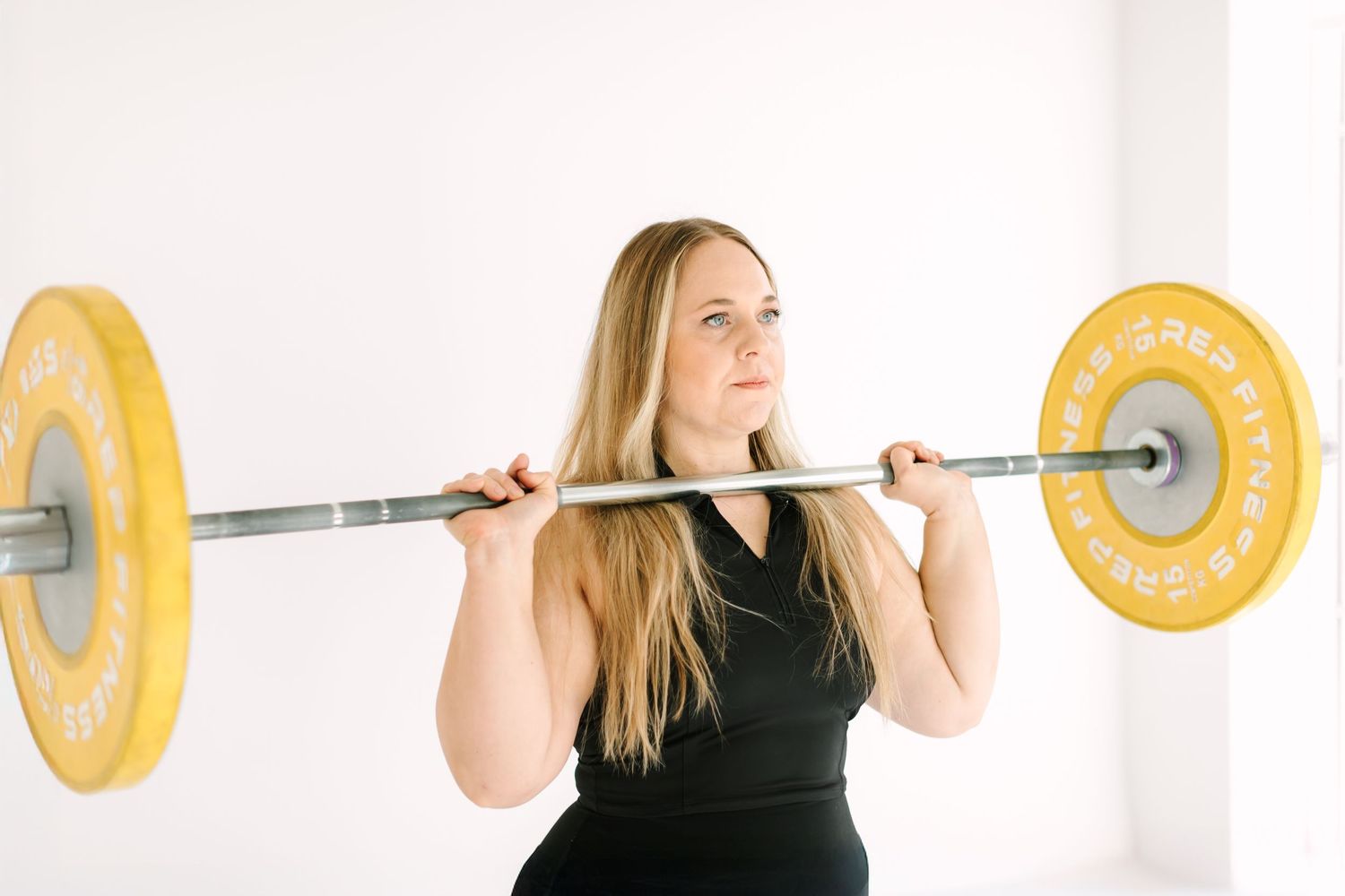 Woman in black tank top performing barbell squats in sequence against white background.