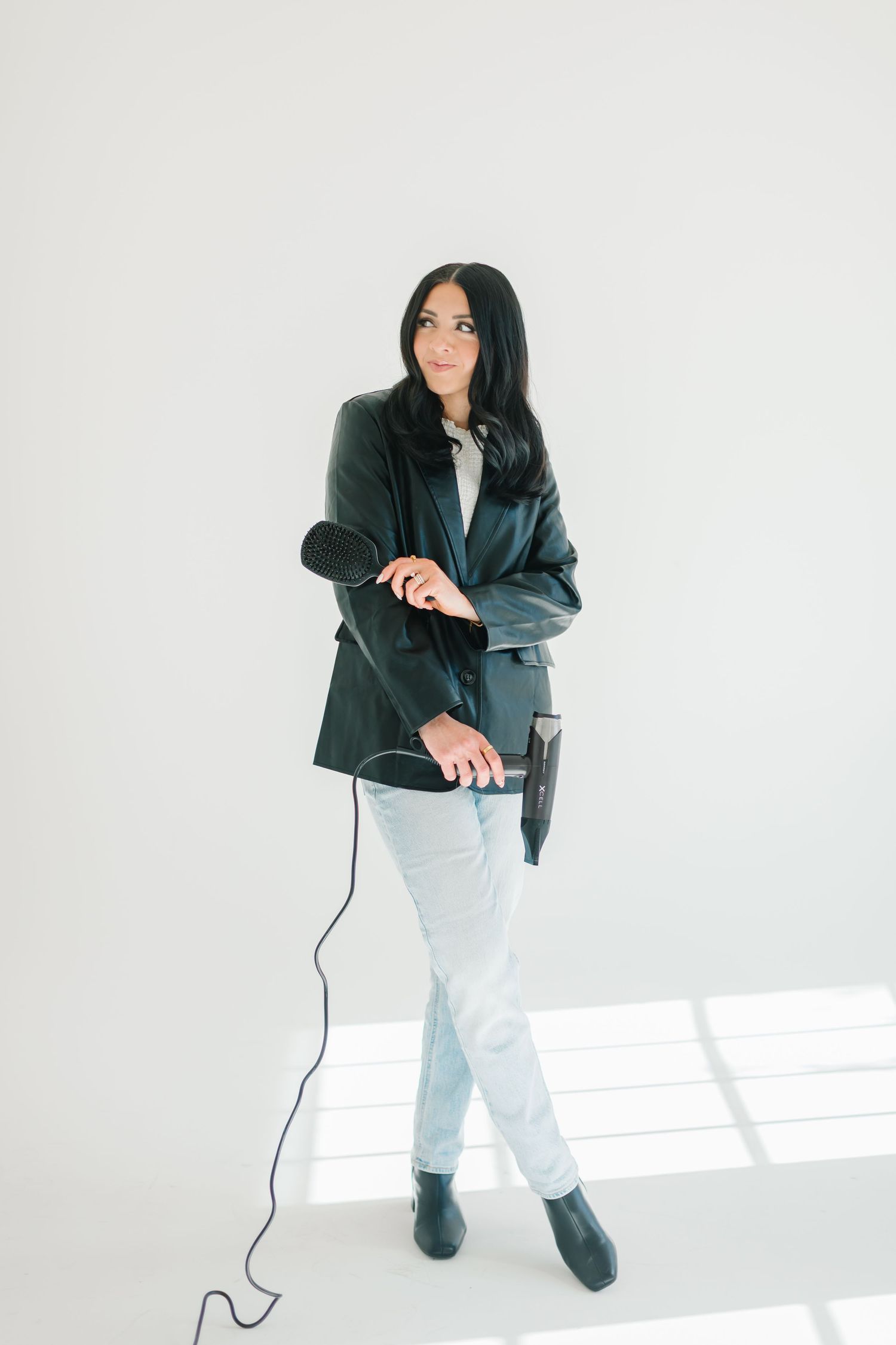 Person in dark jacket and light pants holding microphone cord against white background at White Space Studios in Provo, Utah in Utah County.