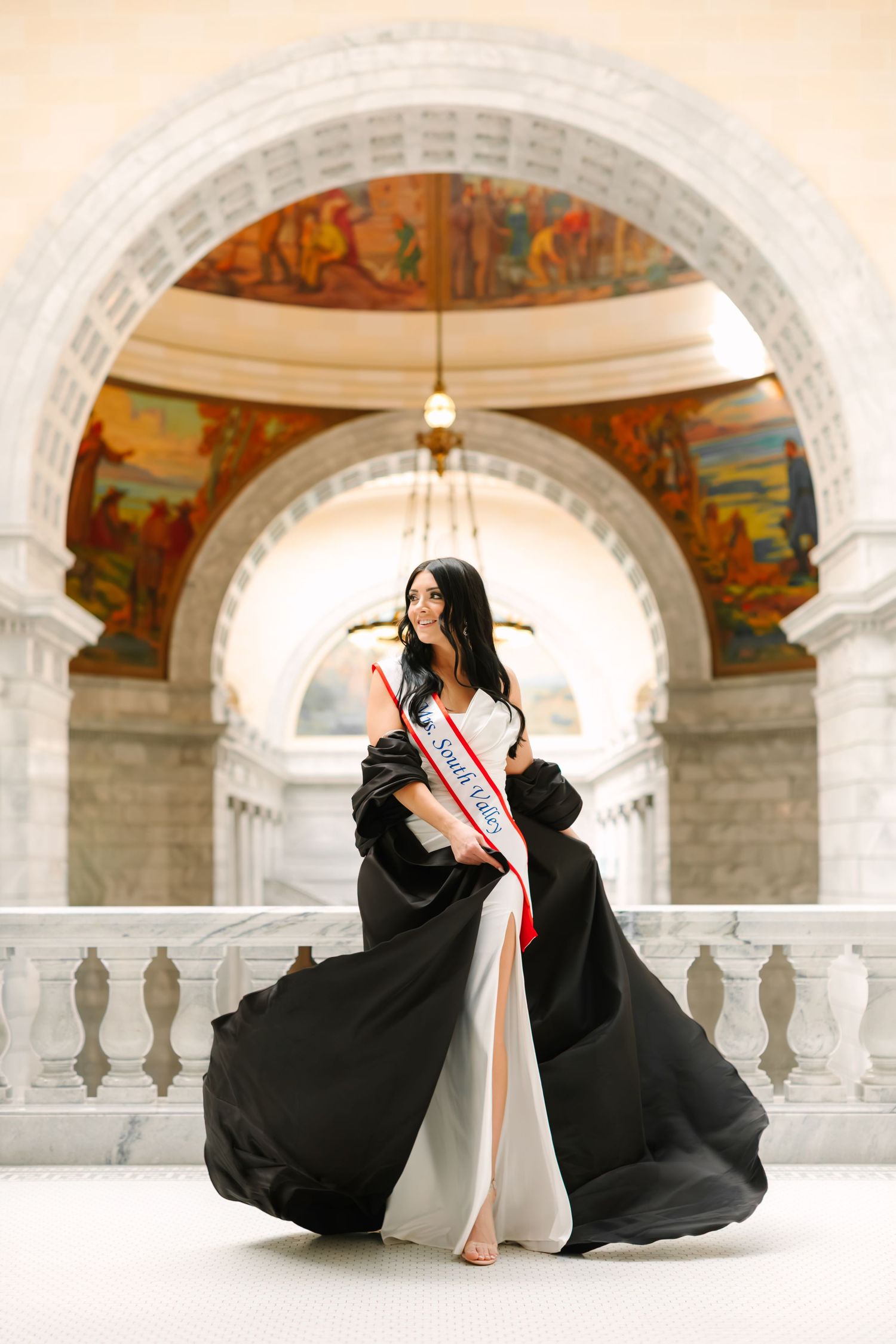 Women in a black and white gown walking through the Utah State Capitol building in Salt Lake City, Utah during her portrait photoshoot.
