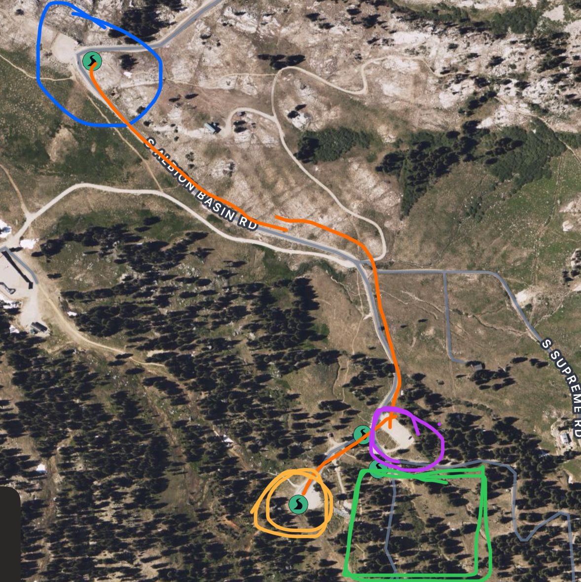 Aerial satellite map view with colored route markers showing trails and points of interest in a mountainous forested area.