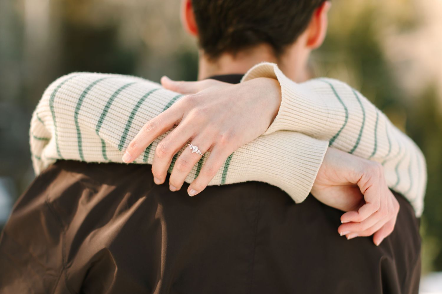 Close-up of hands gently holding and examining a delicate white paper origami creation against a blurred background.