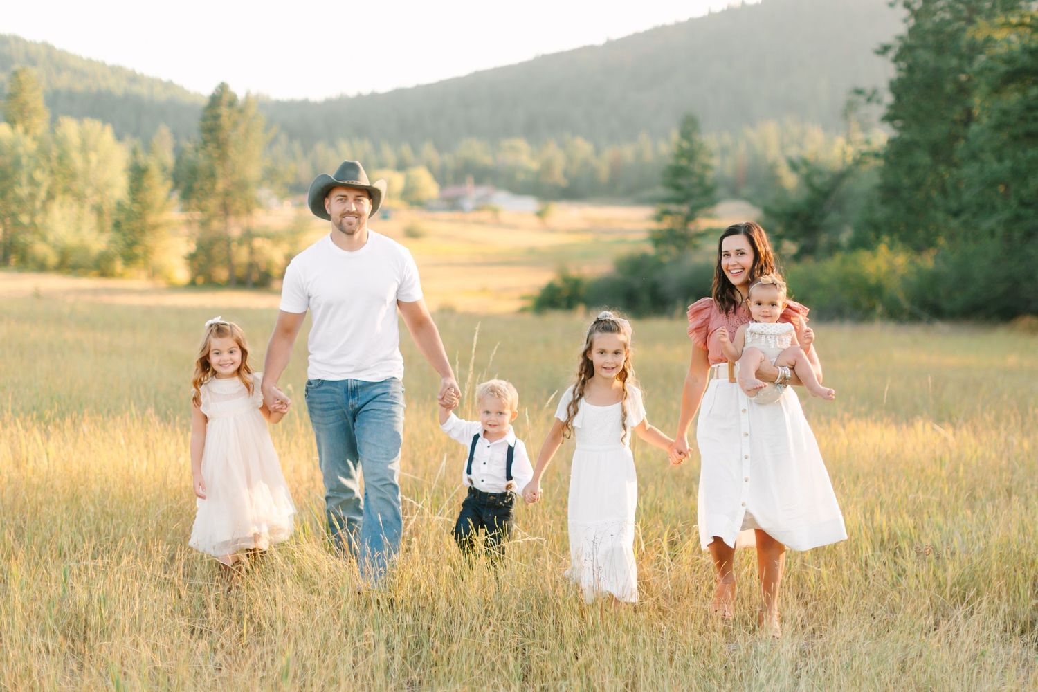 A family runs and plays together in a golden sunlit meadow during sunset.
