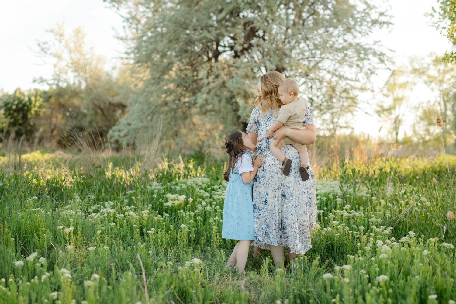 A mom and her three children surrounded by trees and grass at golden hour at Bountiful Pond in Bountiful, Utah during their mini session.
