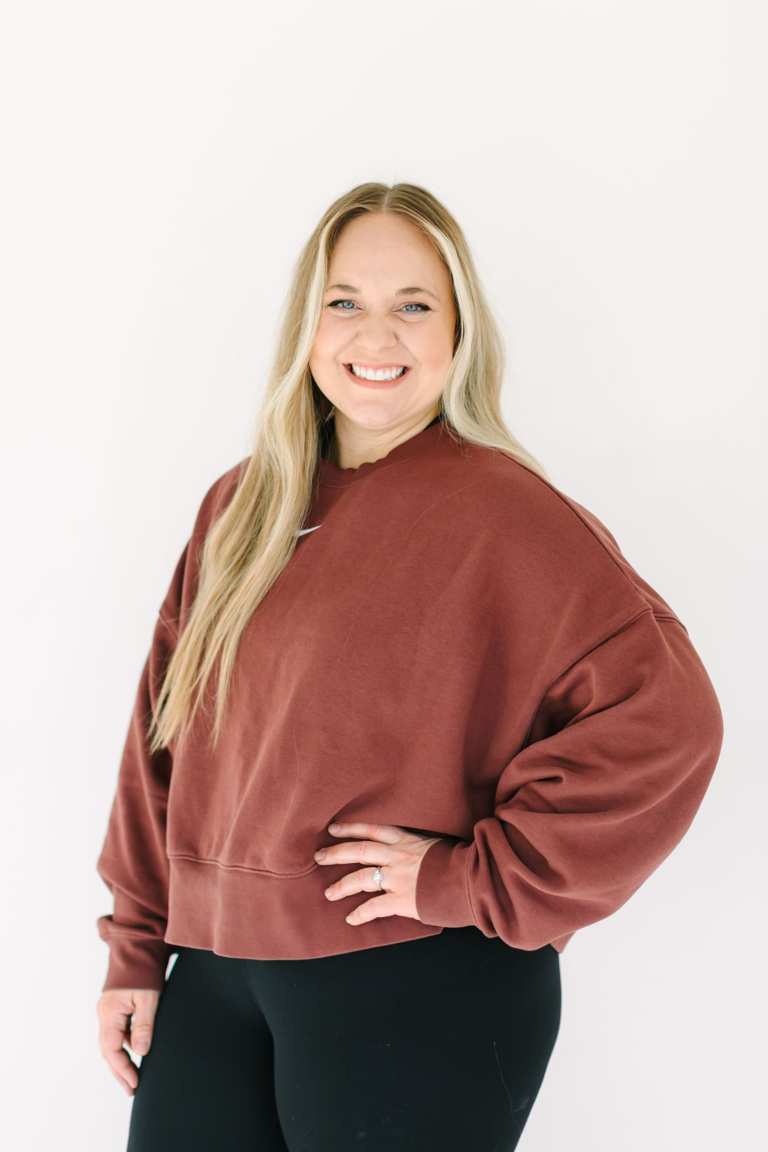 Woman in a rust-colored cropped sweatshirt and black pants poses confidently in multiple angles.