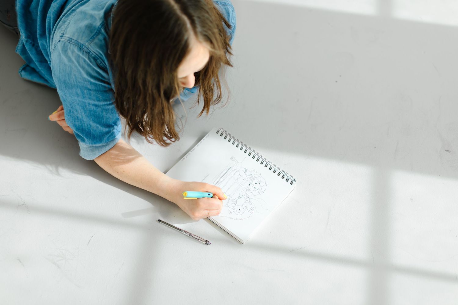 Woman writing in notebook on white desk with natural lighting and shadows at White Space Studio in Provo, Utah in Utah County.