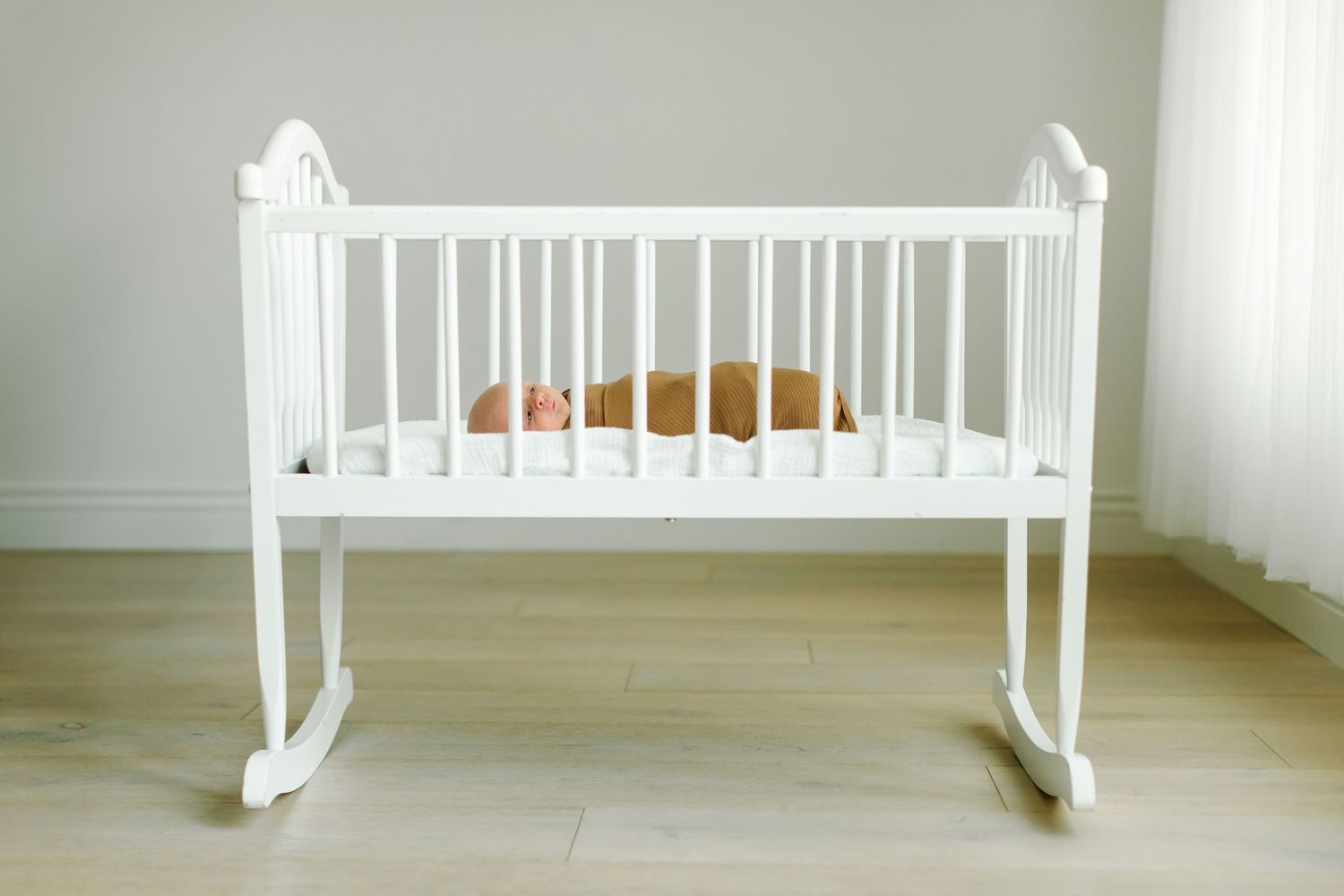 A white wooden baby cradle photographed from different angles in a minimalist room setting at White Space Studios in Provo, Utah.