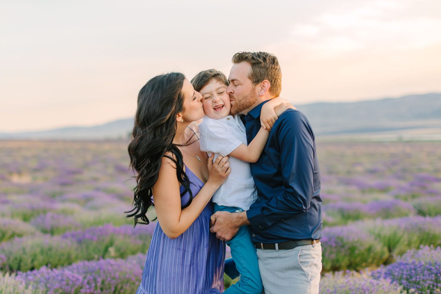 Family shares tender moments together in a blooming purple lavender field at sunset.
