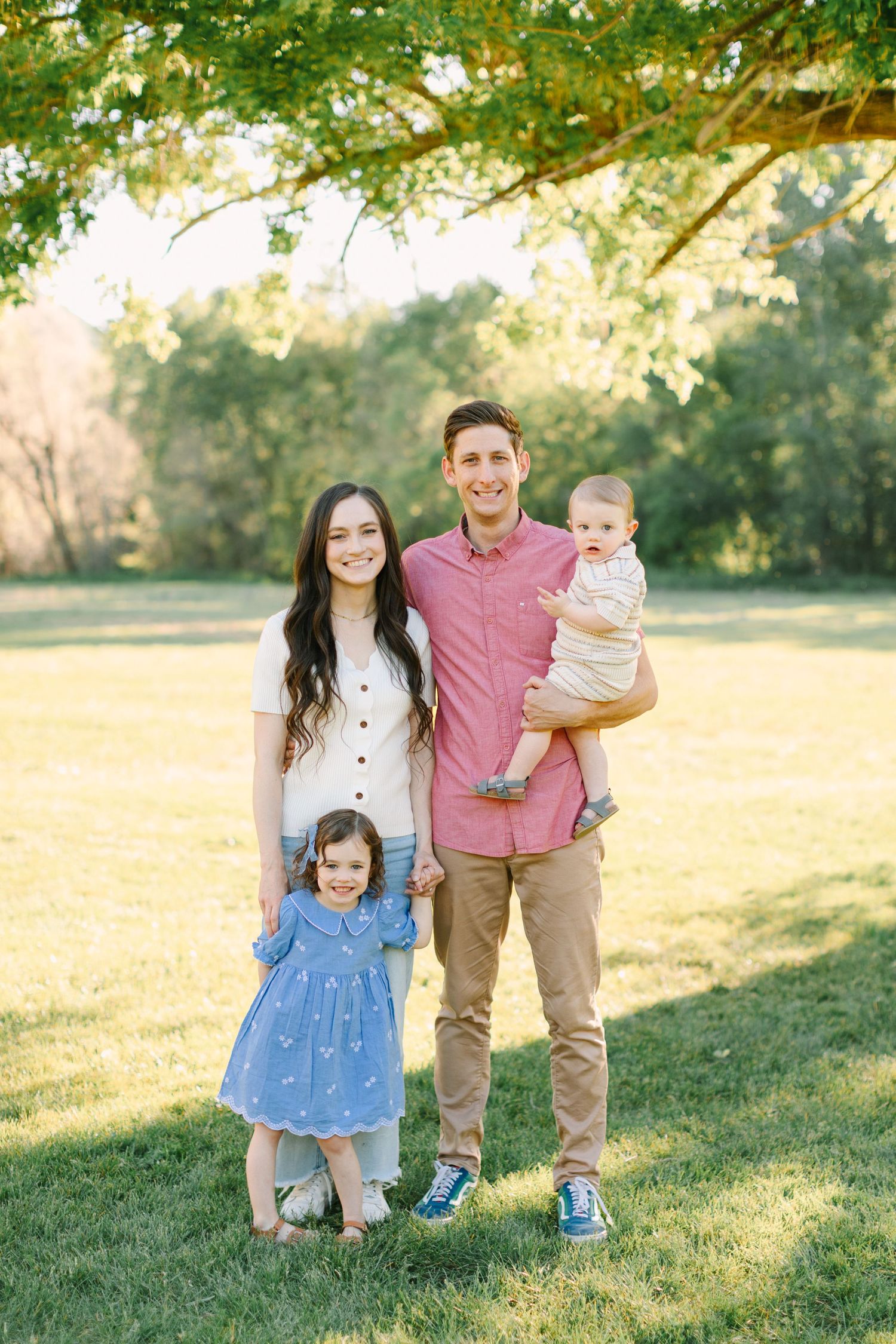 Family enjoying a golden sunset in a grassy park wearing coordinated pink and blue outfits.