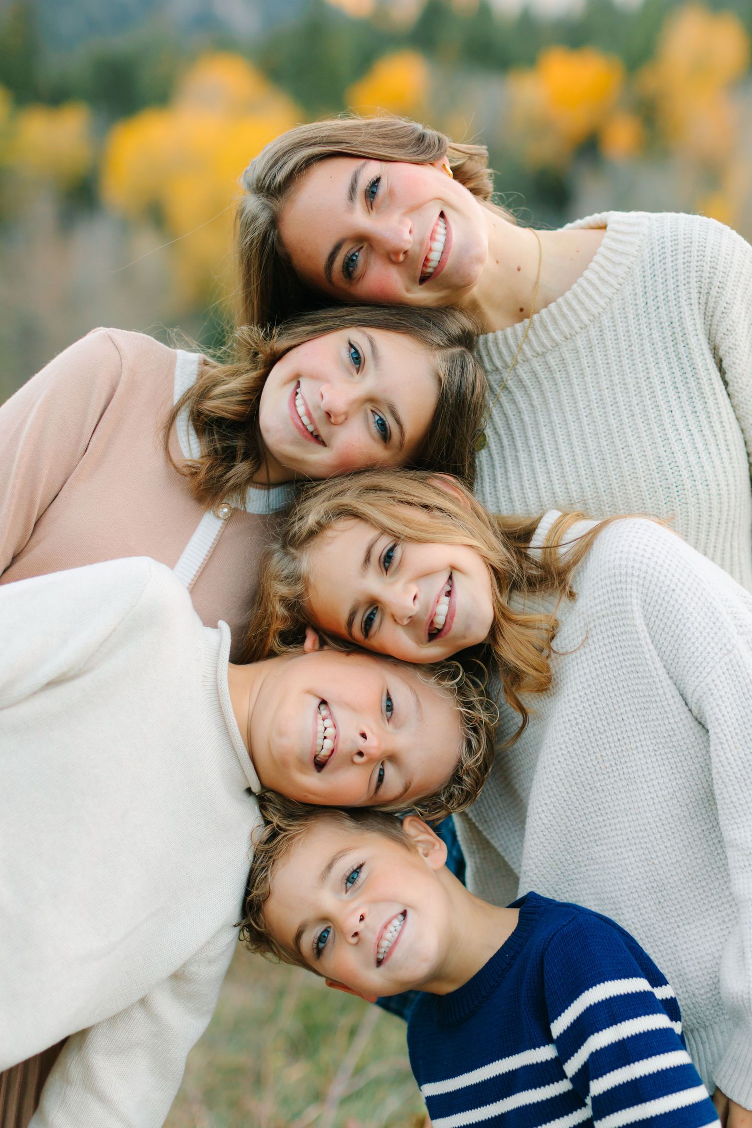 Candid lifestyle portrait series showing tender moments between parent and child in matching sweaters against autumn foliage.