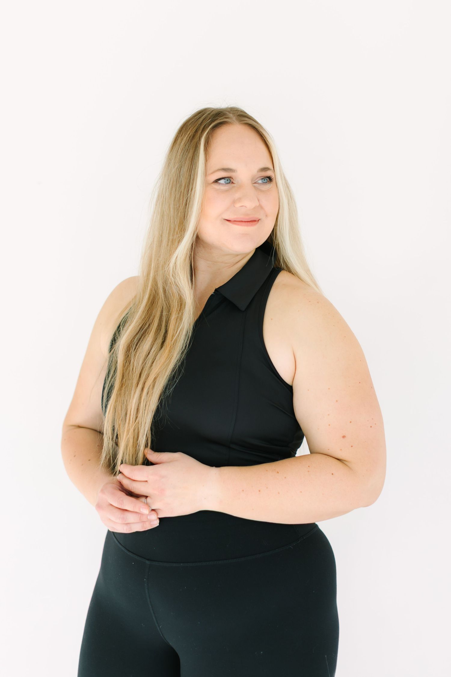 A person in a black sleeveless top poses confidently in a series of body-positive studio portraits against a white backdrop.