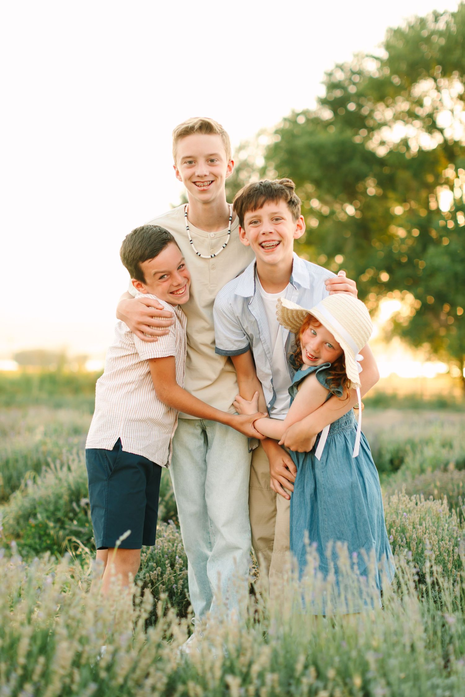 Family embraces in a golden field of lavender during sunset, creating a joyful candid moment.