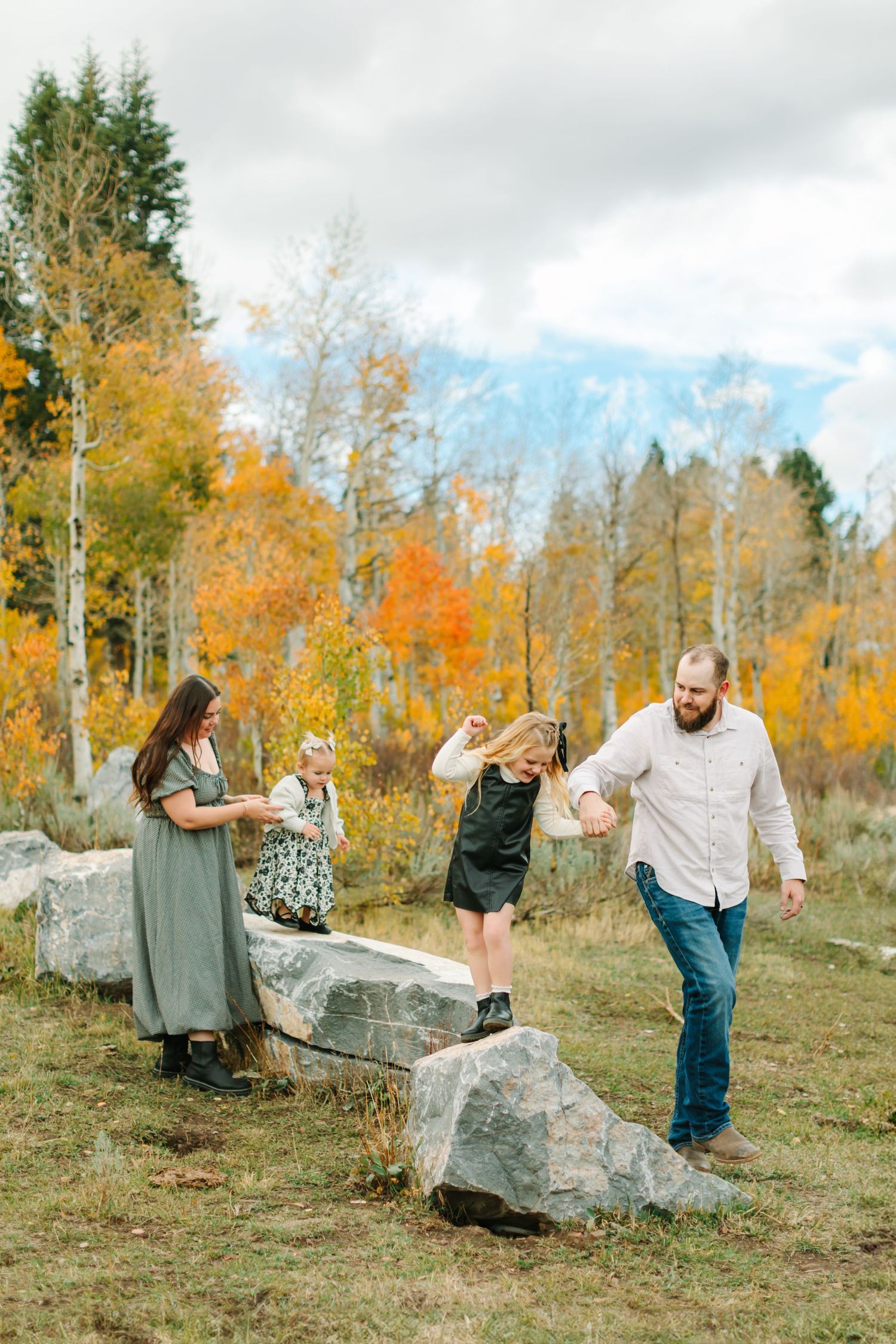 People enjoying a playful moment together on rocks during autumn with colorful aspen trees in the background.
