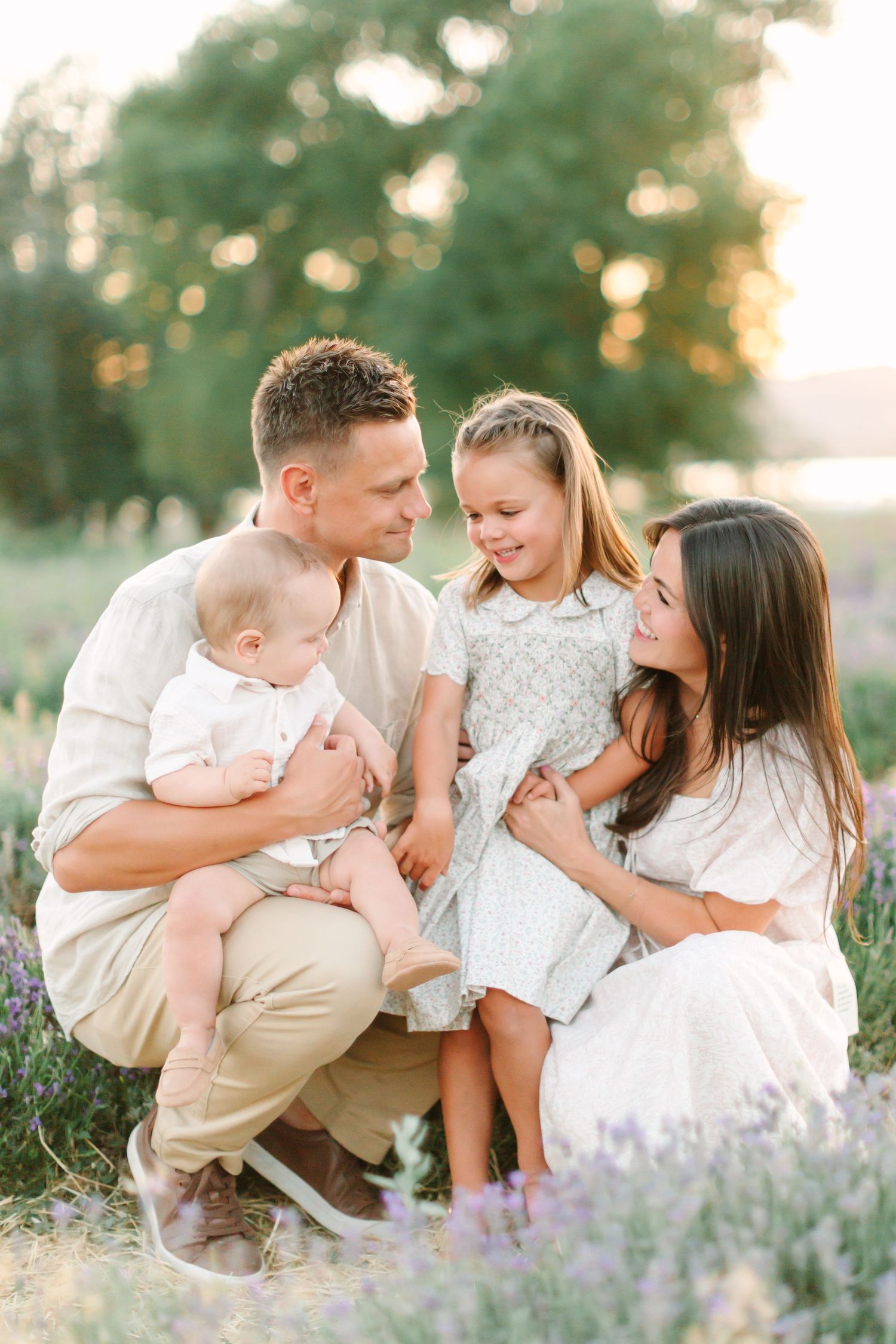 A family shares tender moments together in a blooming lavender field during golden hour.