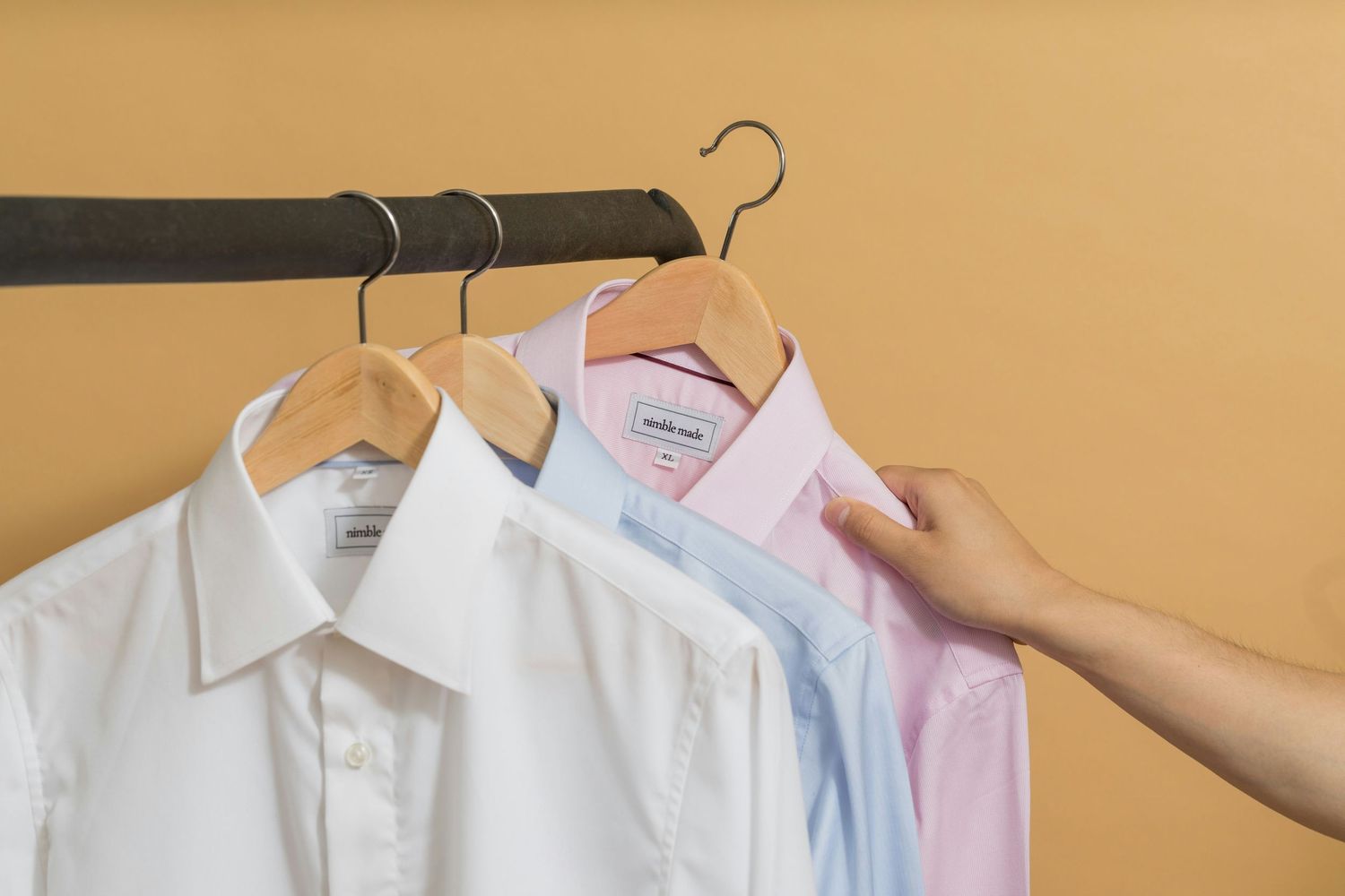 White, blue and pink button-down shirts on hangers as wardrobe options for a professional business headshot session.