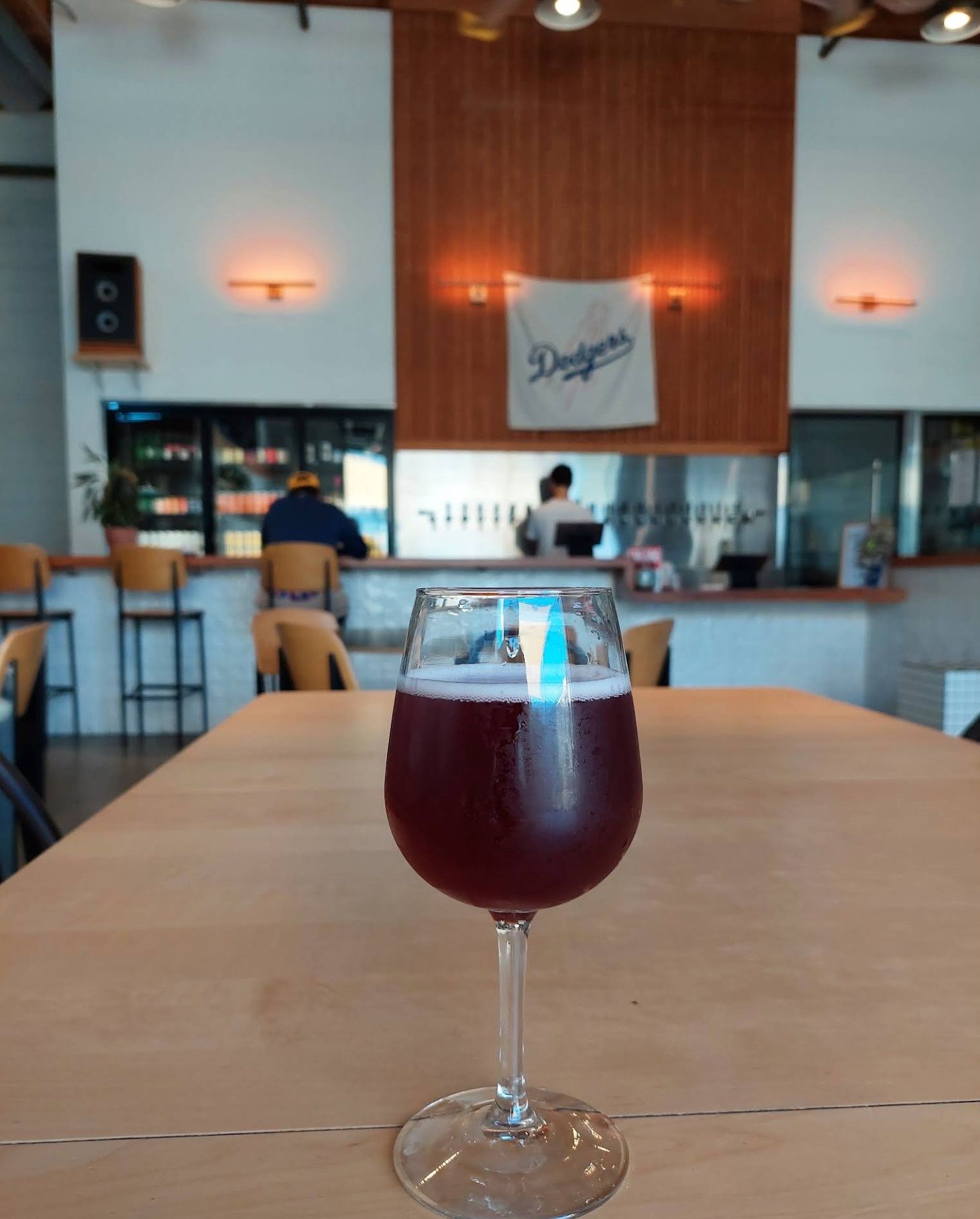 Sour beer in tap room with a Los Angeles Dodgers flag behind the bar at Homage Brewing.